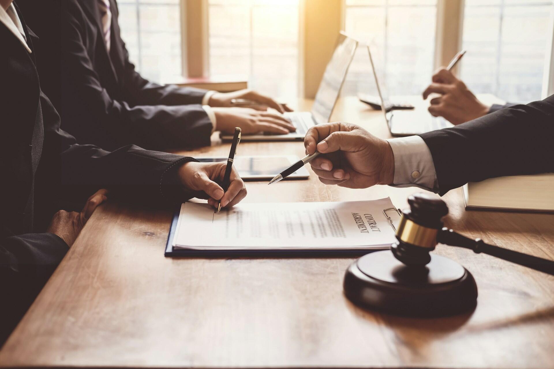 clients reviewing and signing contract papers presented by a lawyer in a well-lit office space