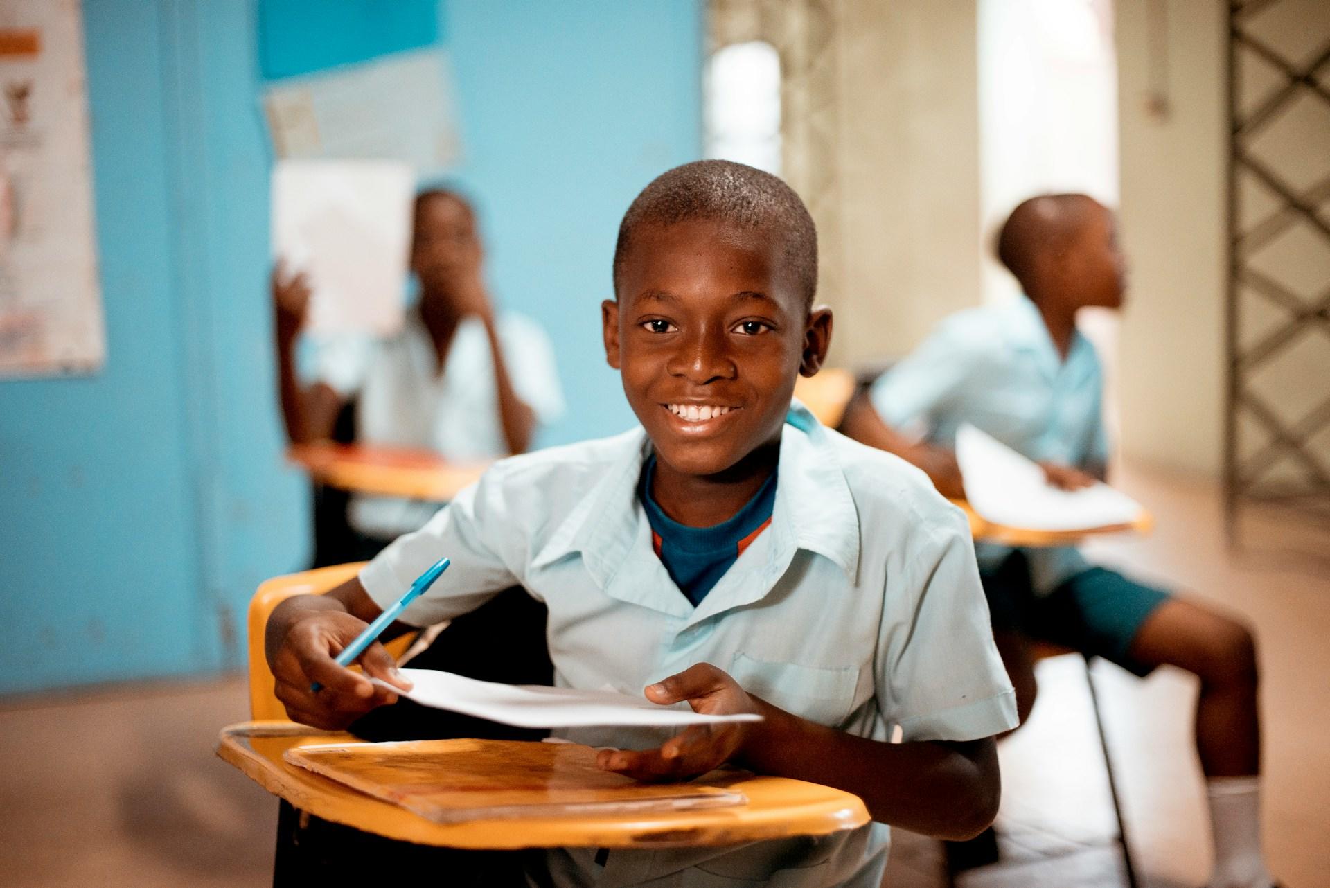 a young boy sitting at a desk in a classroom.