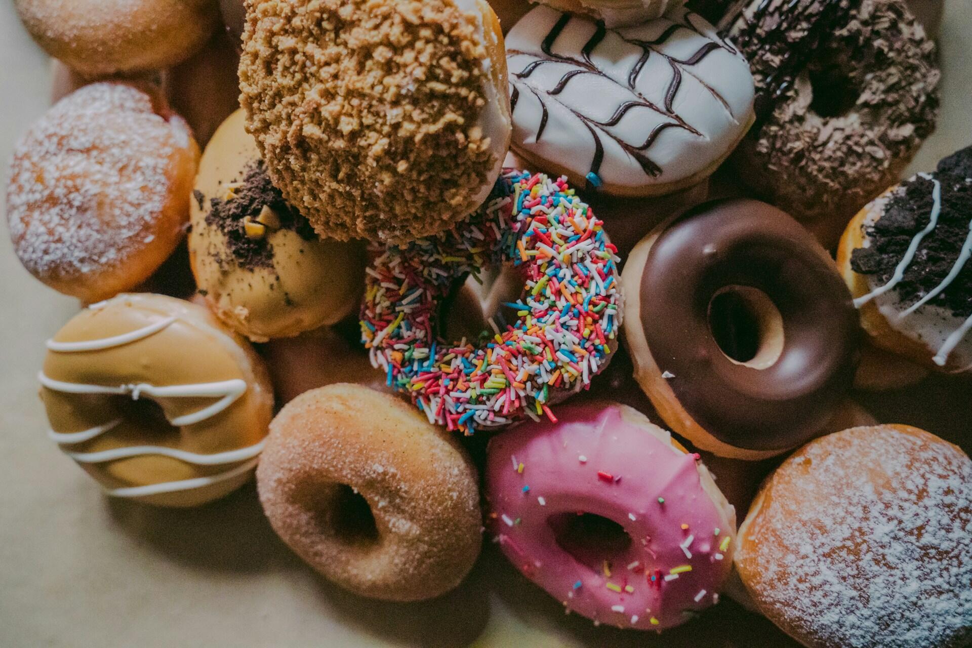 a pile of decorated doughnuts with various frostings and sprinkles on top