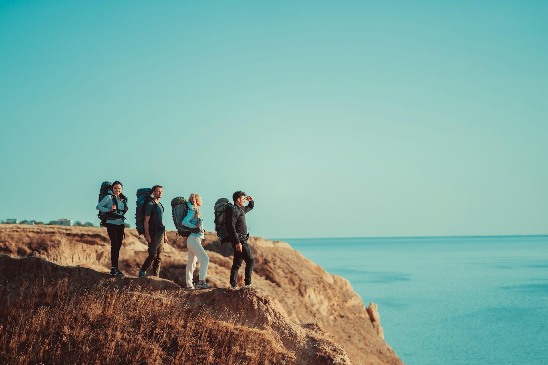 group of friends on top of a mountain, looking out over the ocean