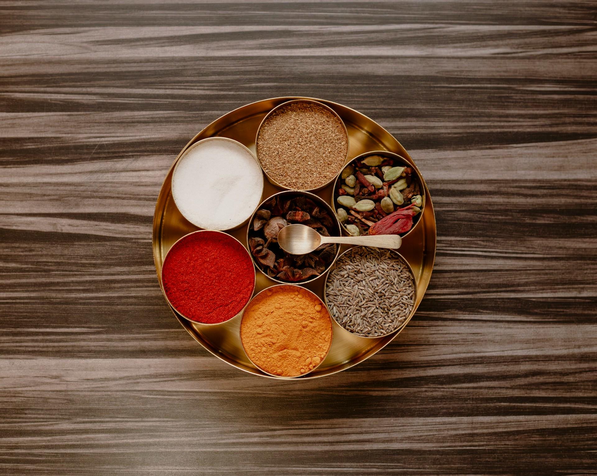 A bowl of different spices on a wooden table.