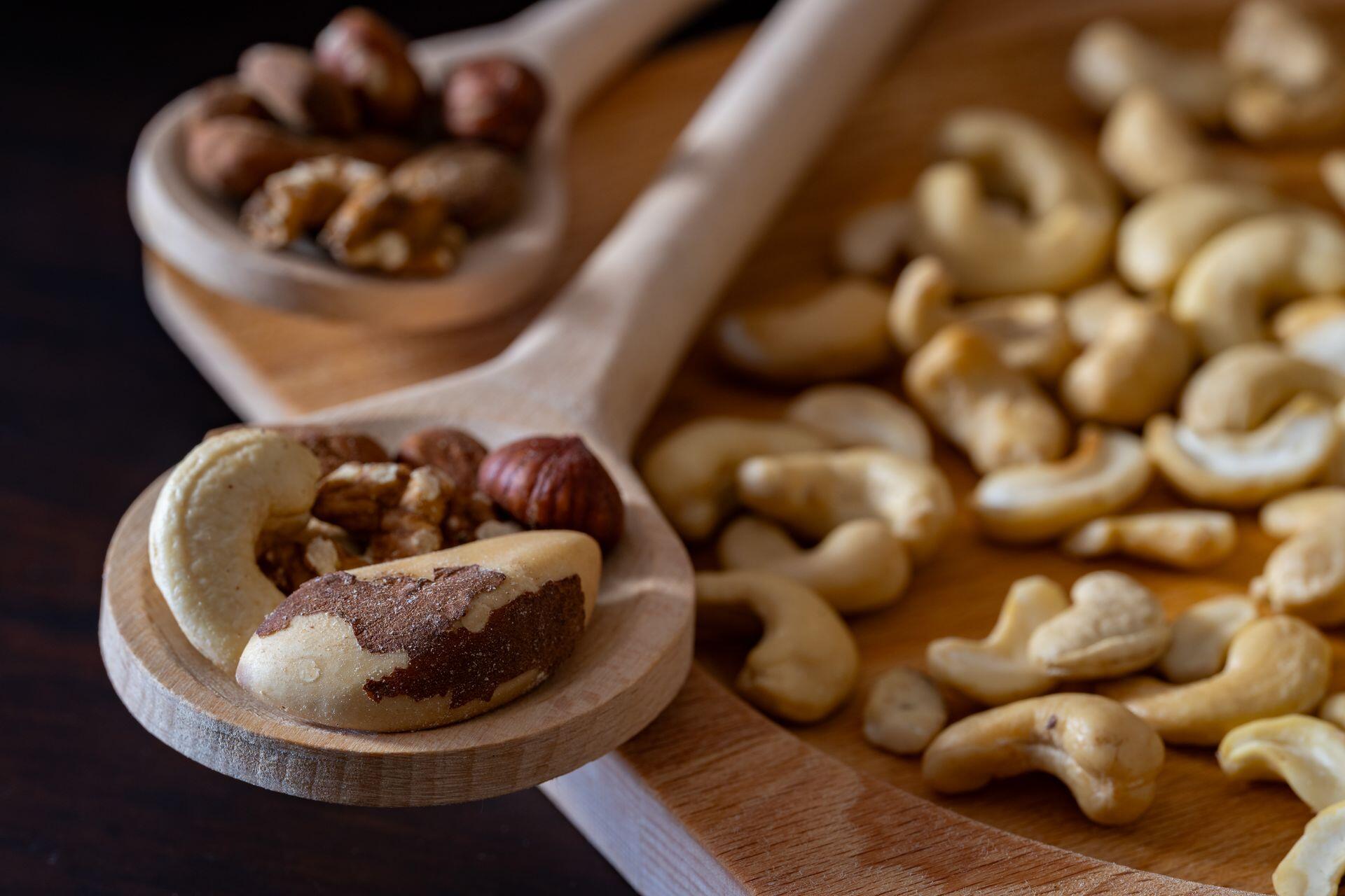 Cashews, Brazil nuts, hazelnuts, and walnuts on a wooden spoon and wooden board