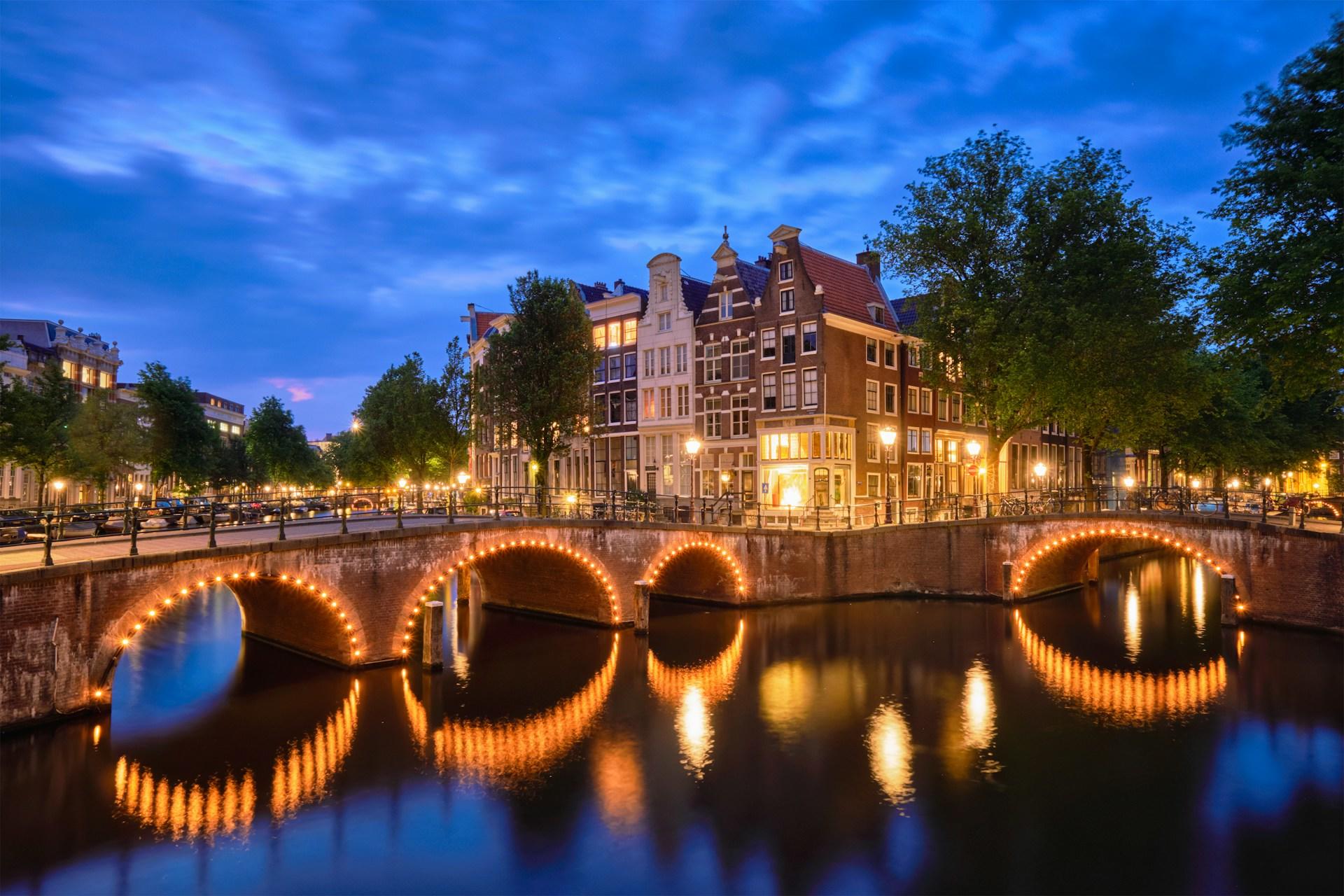 A night view of Amsterdam landscape featuring canals and historic buildings.