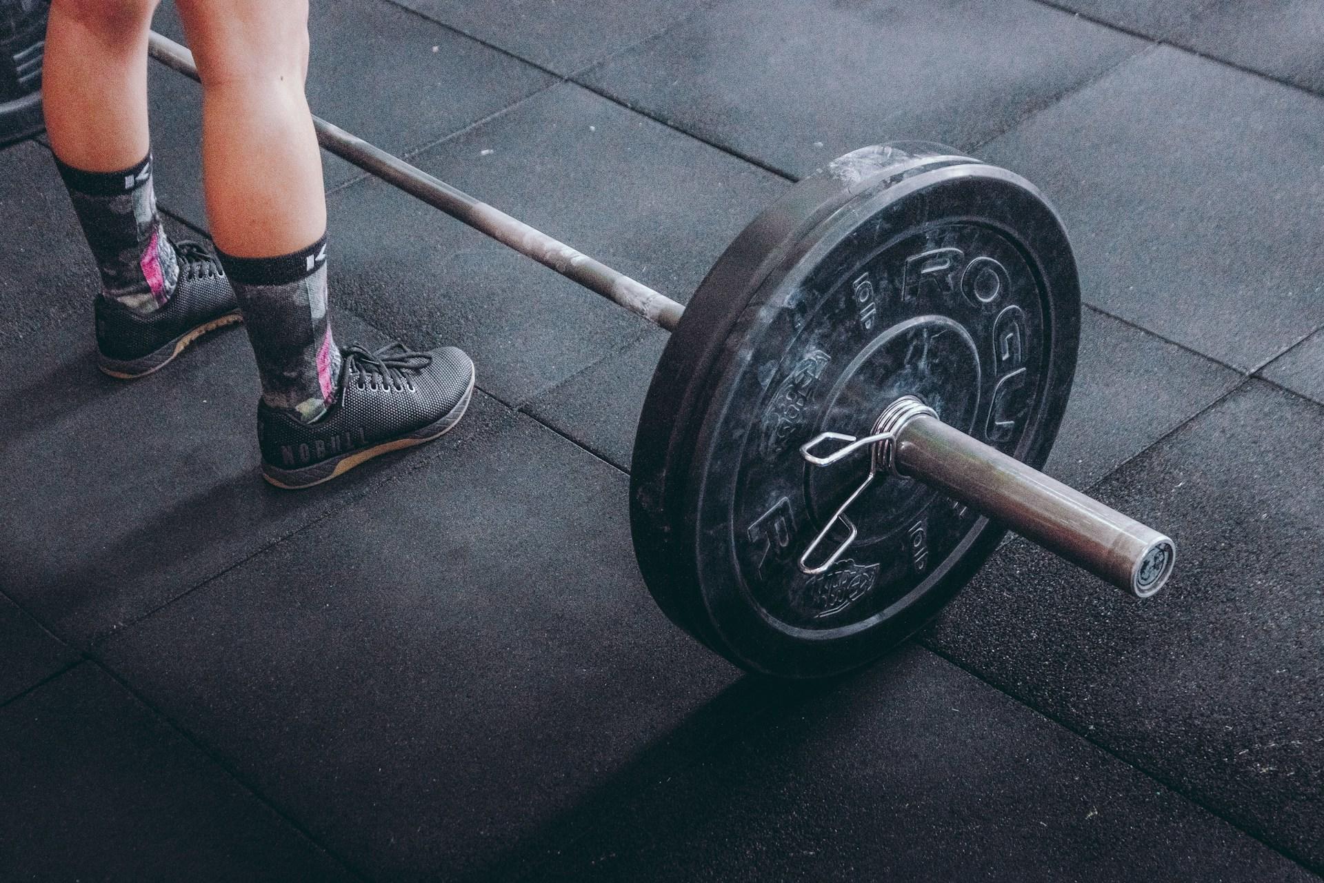A person standing next to a barbell.