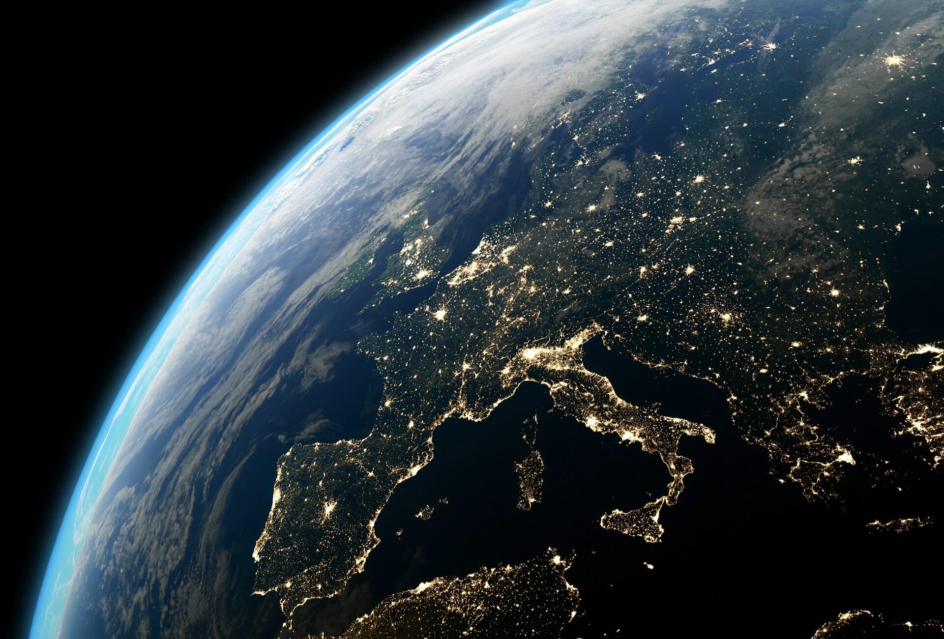 Earth from space at night with city lights outlining the continents.