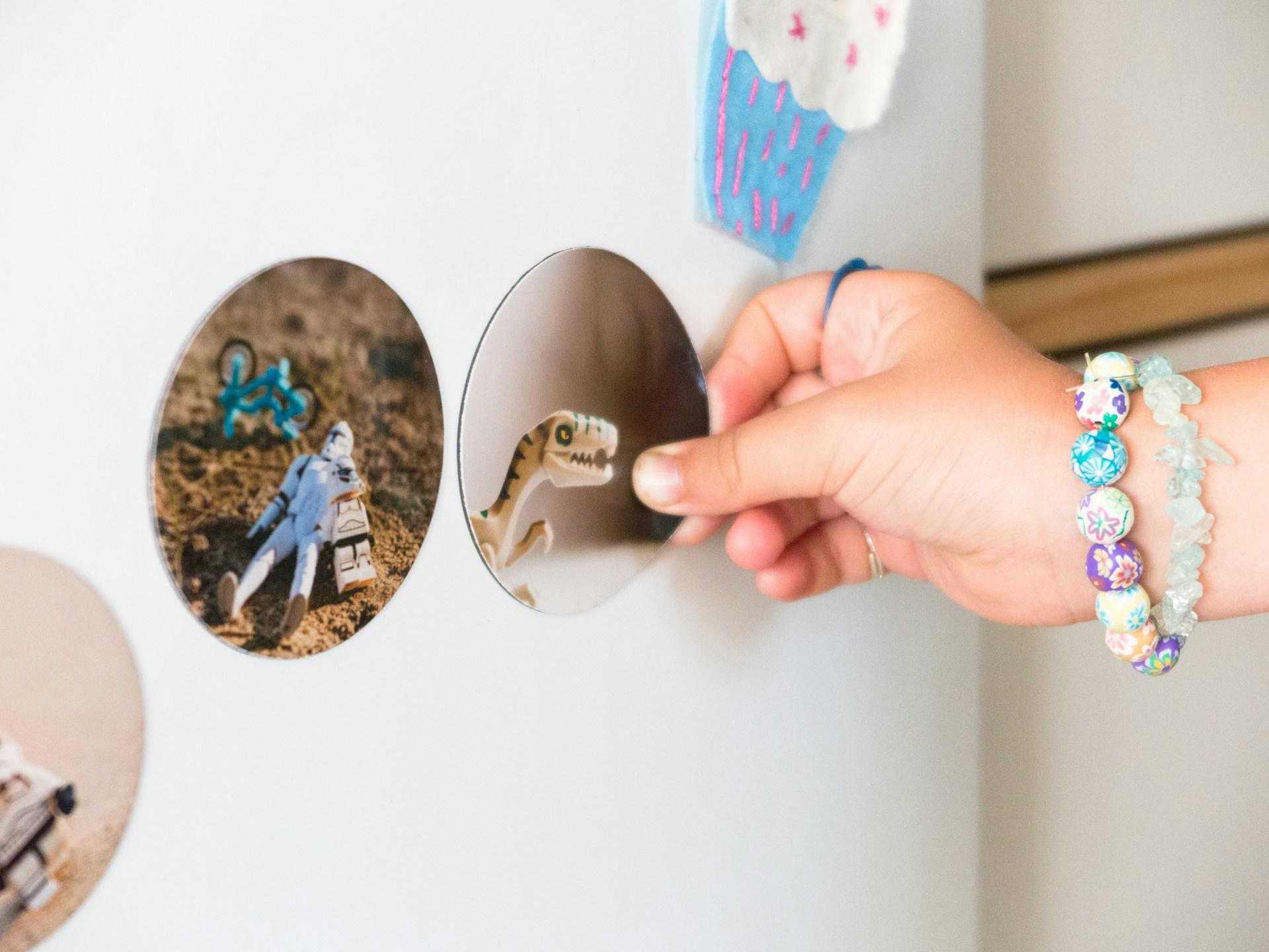 A kid's hand holding a magnet on a refrigerator.