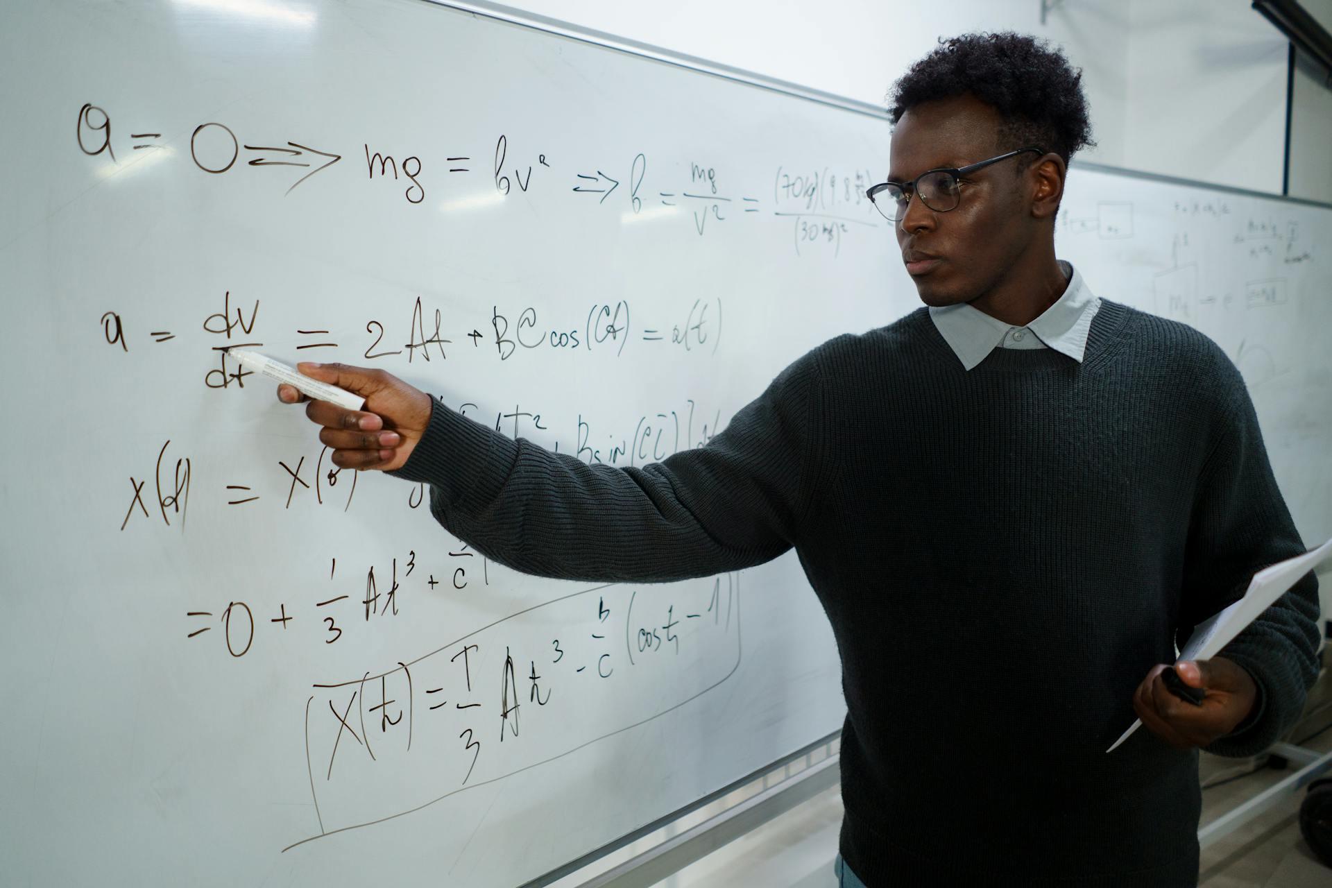 A maths teacher writing equations on a whiteboard