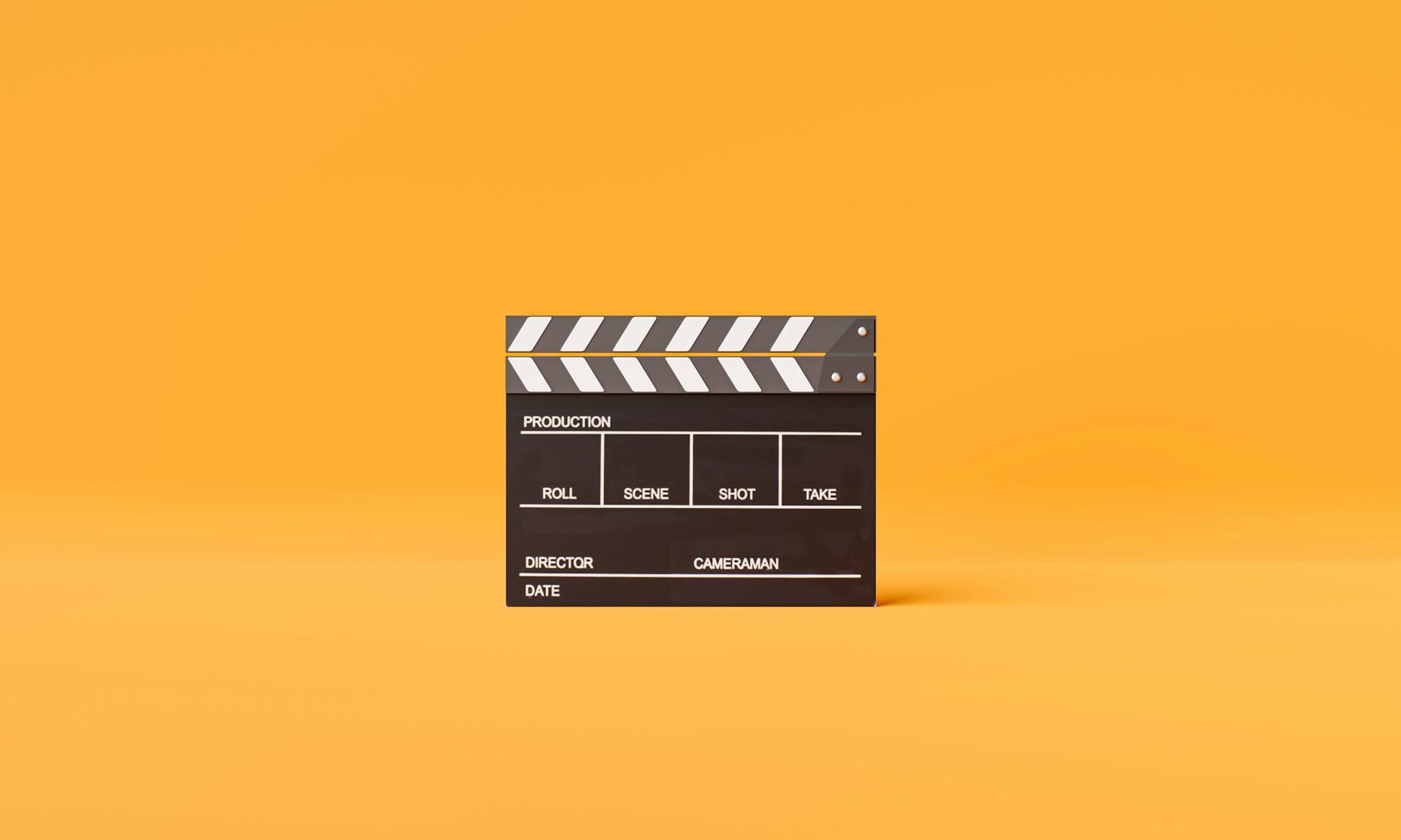 A movie clapperboard on a plain orange background.