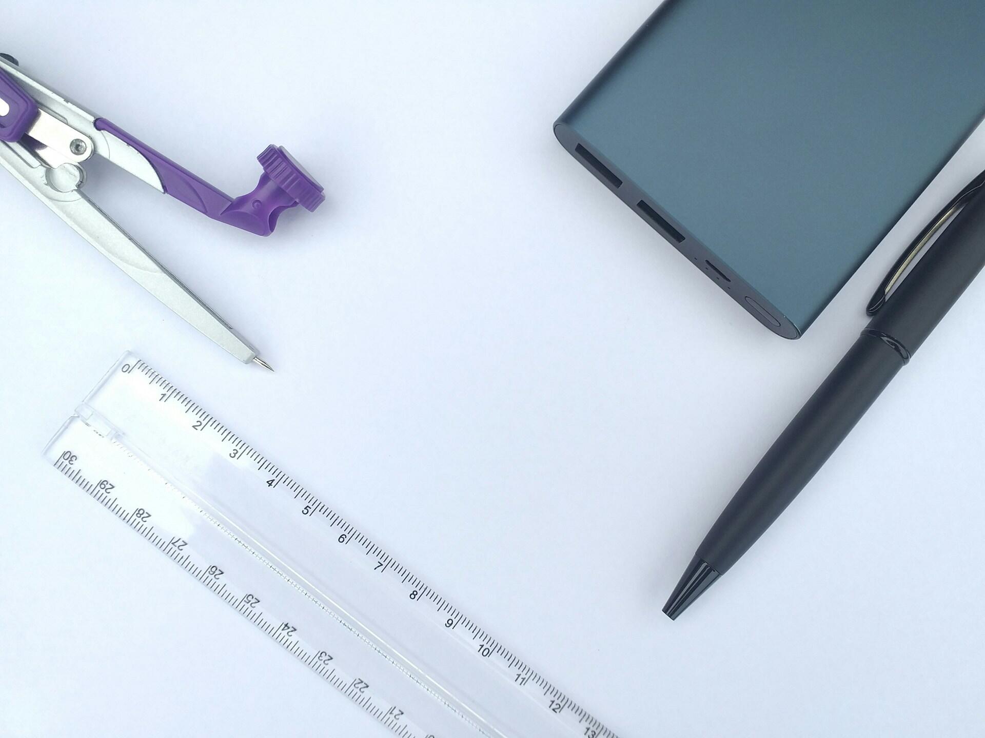 A compass, calculator, pen, and ruler on a white background.