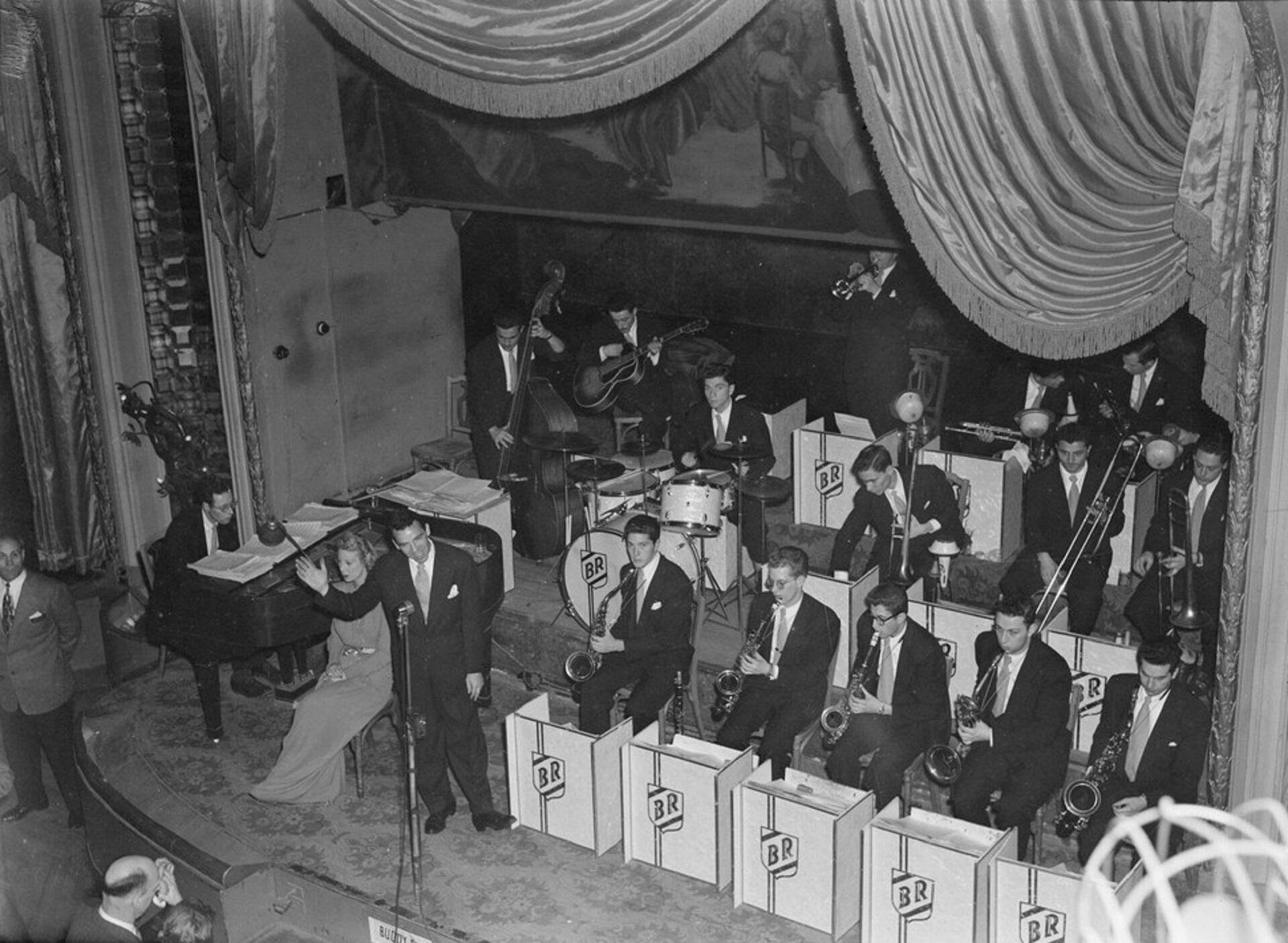 An orchestra band whose members are all wearing suits and ties and holding instruments.