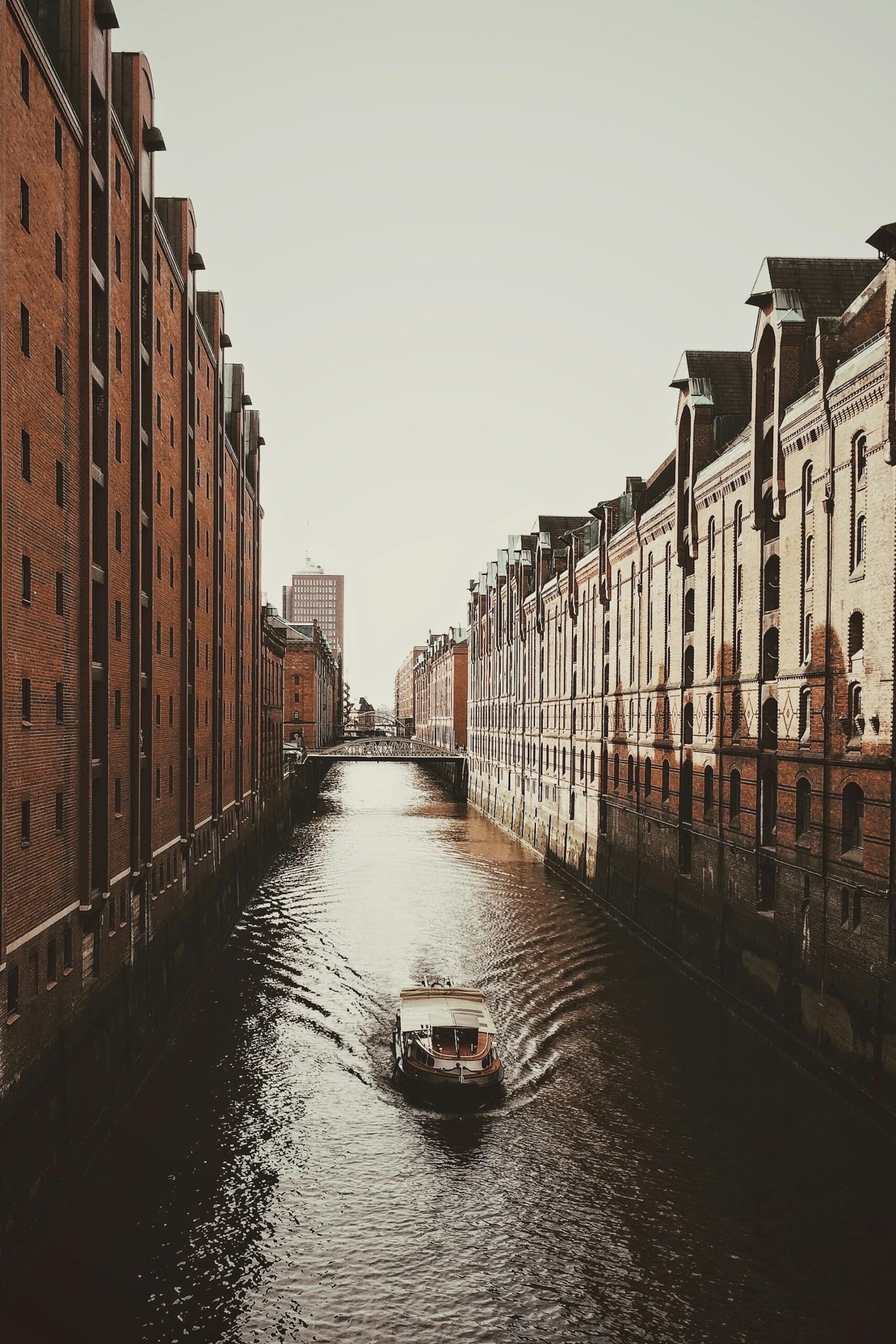 A boat on a canal between tall buildings.  