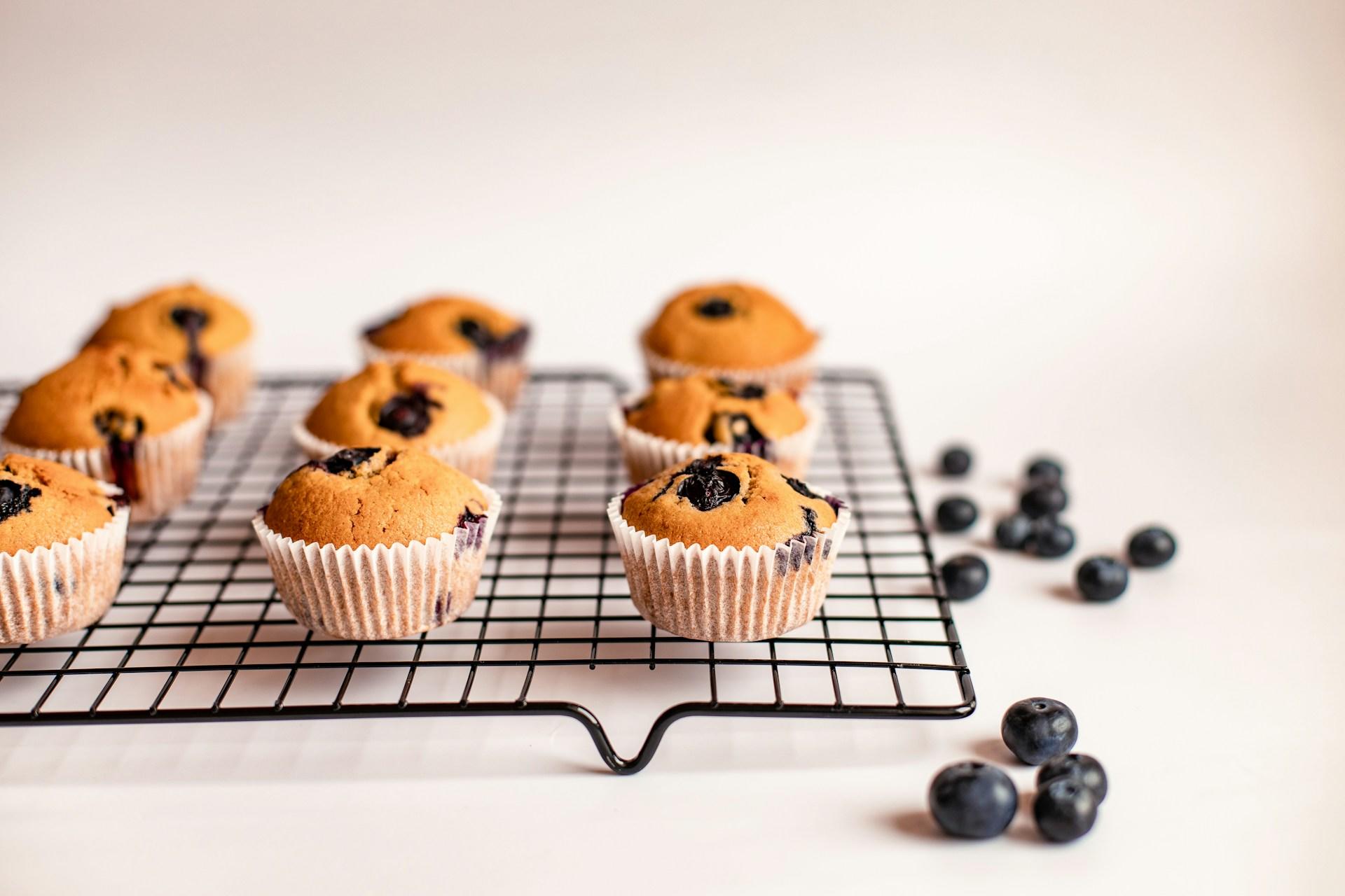 Blueberry muffins cooling on a rack, their golden tops glistening, ready to be devoured.