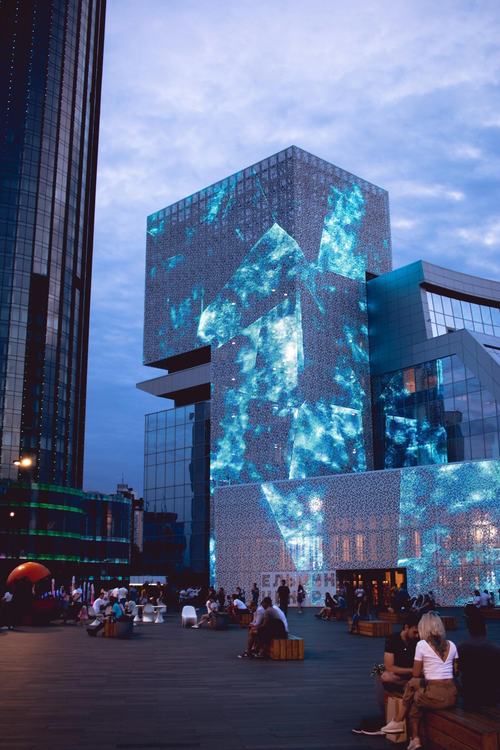 A city square at dusk with people lounging about.