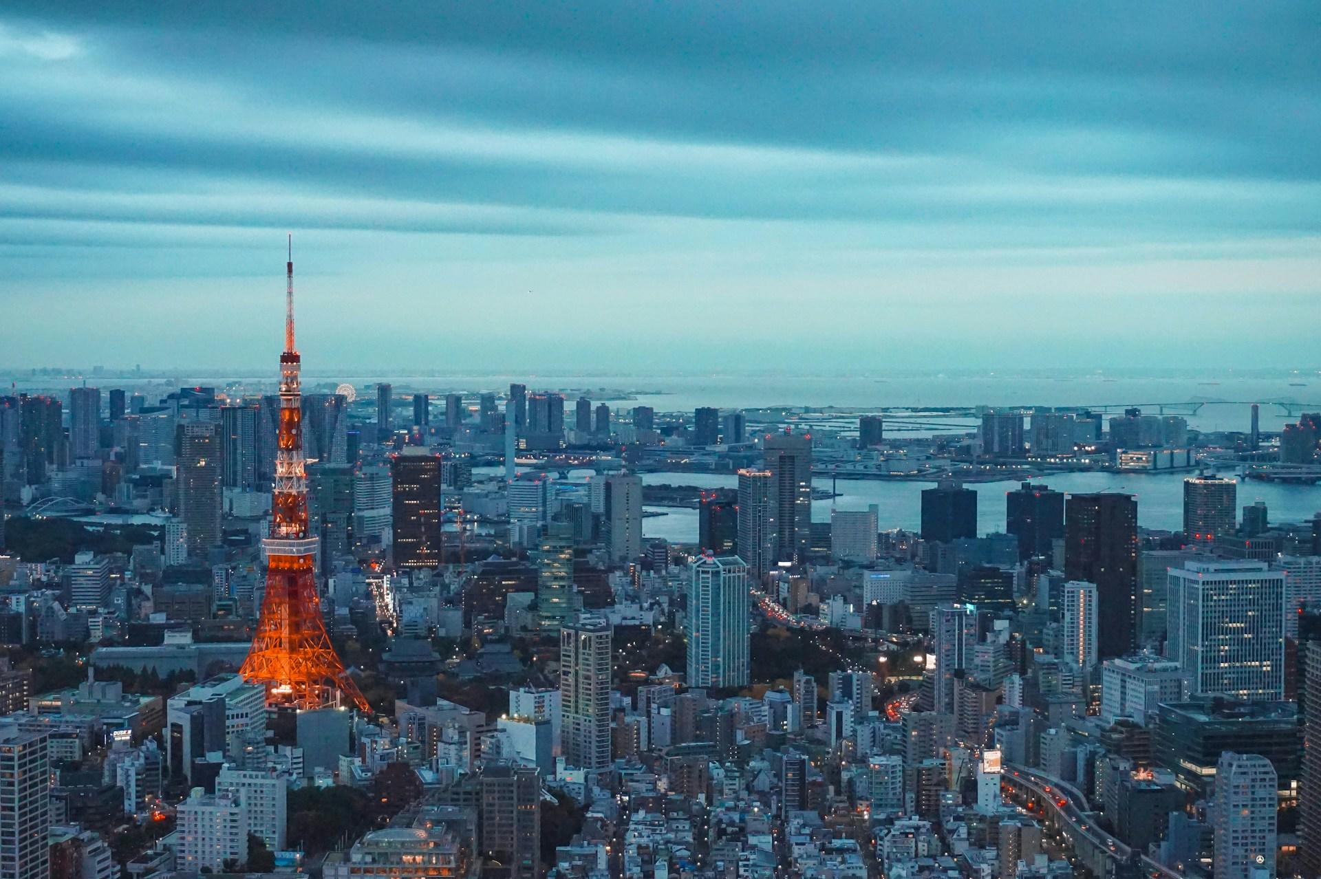 Tokyo Tower standing tall against a dusky sky, illuminating the city with its vibrant lights.
