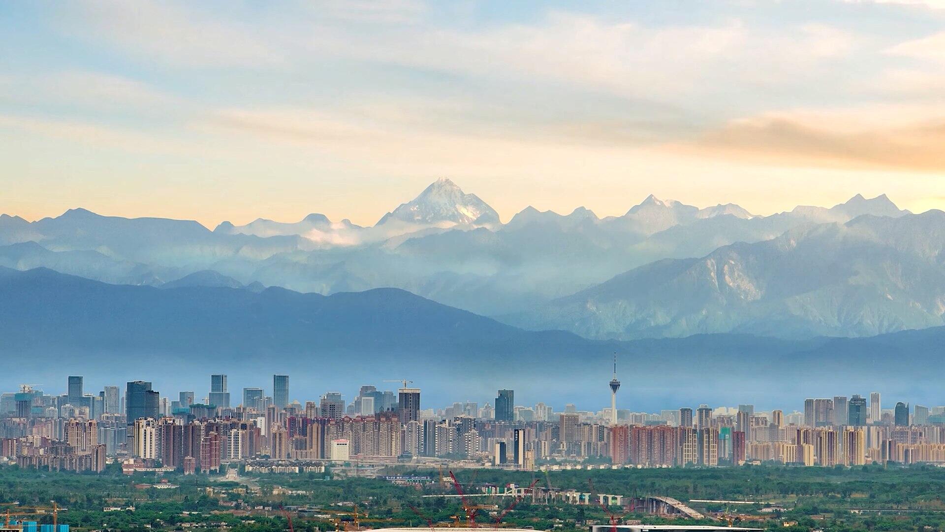 A city at the foot of a mountain at sunrise. 
