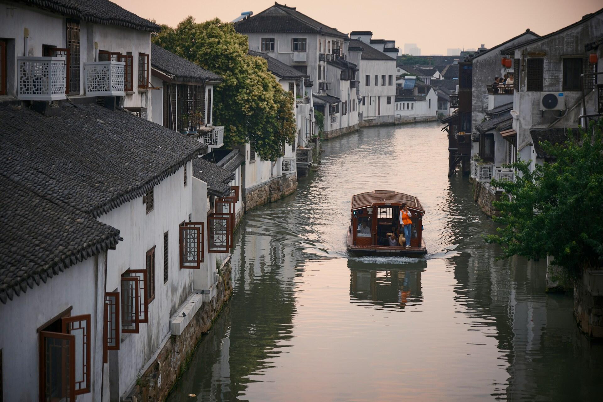 A boat on a canal between houses. 