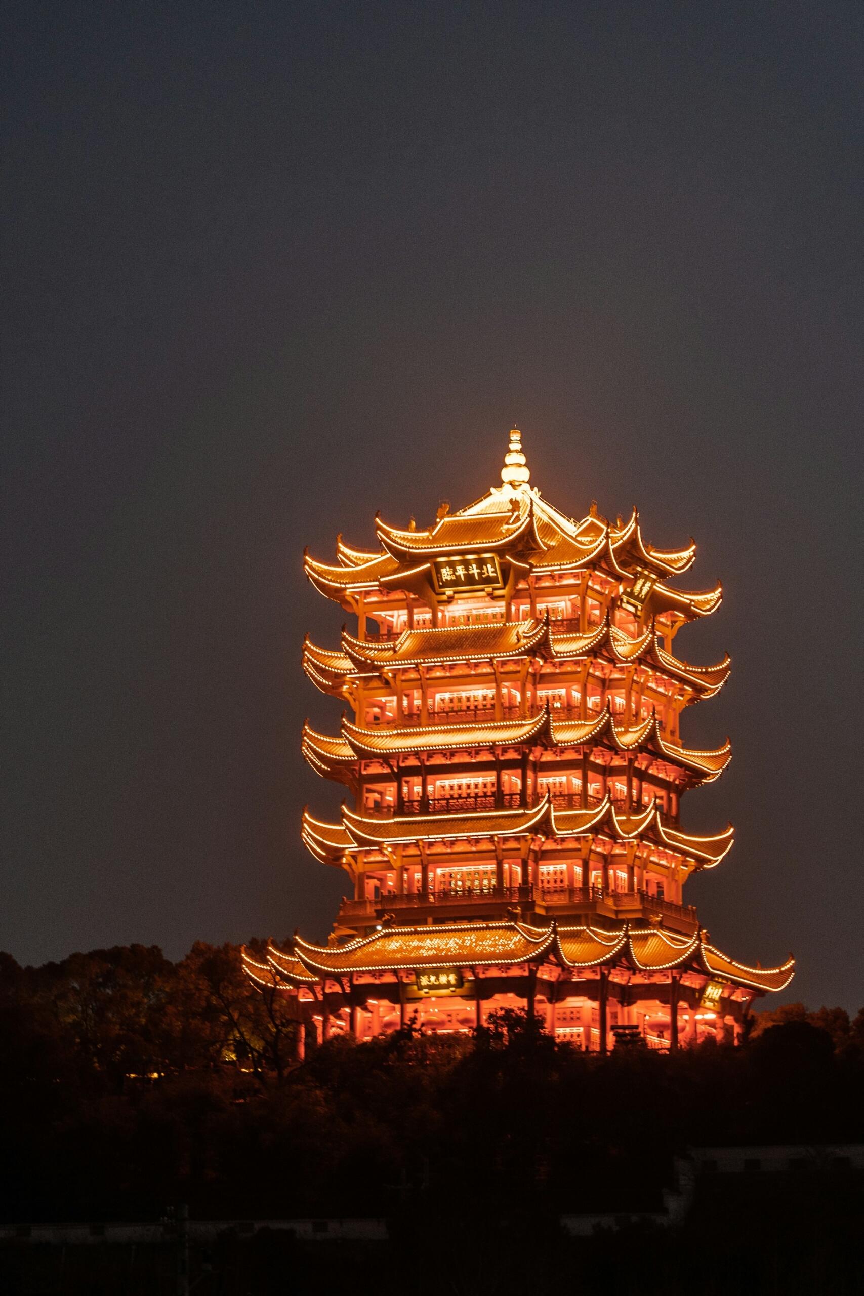 A pagoda lit up in orange against the night sky. 
