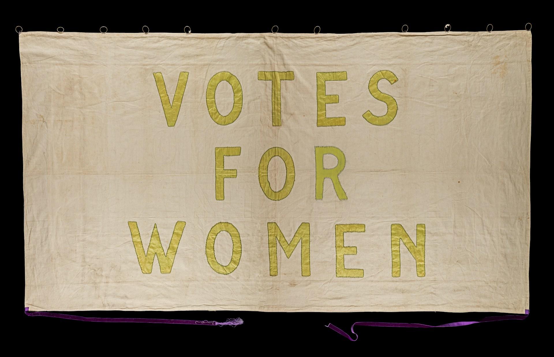 a banner with votes for women written on it