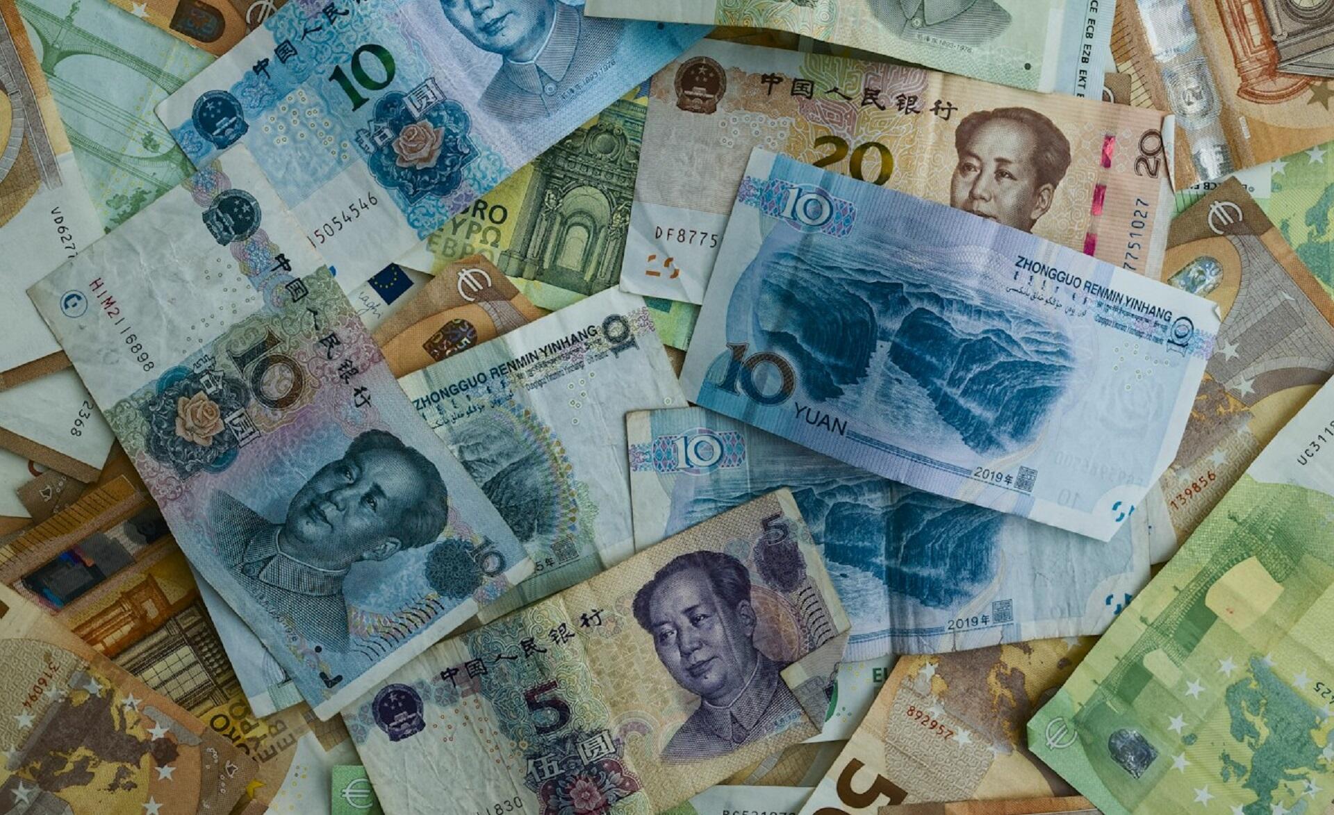 An assortment of Chinese 10-yuan bills and 50-Euro bills scattered in a haphazard way.