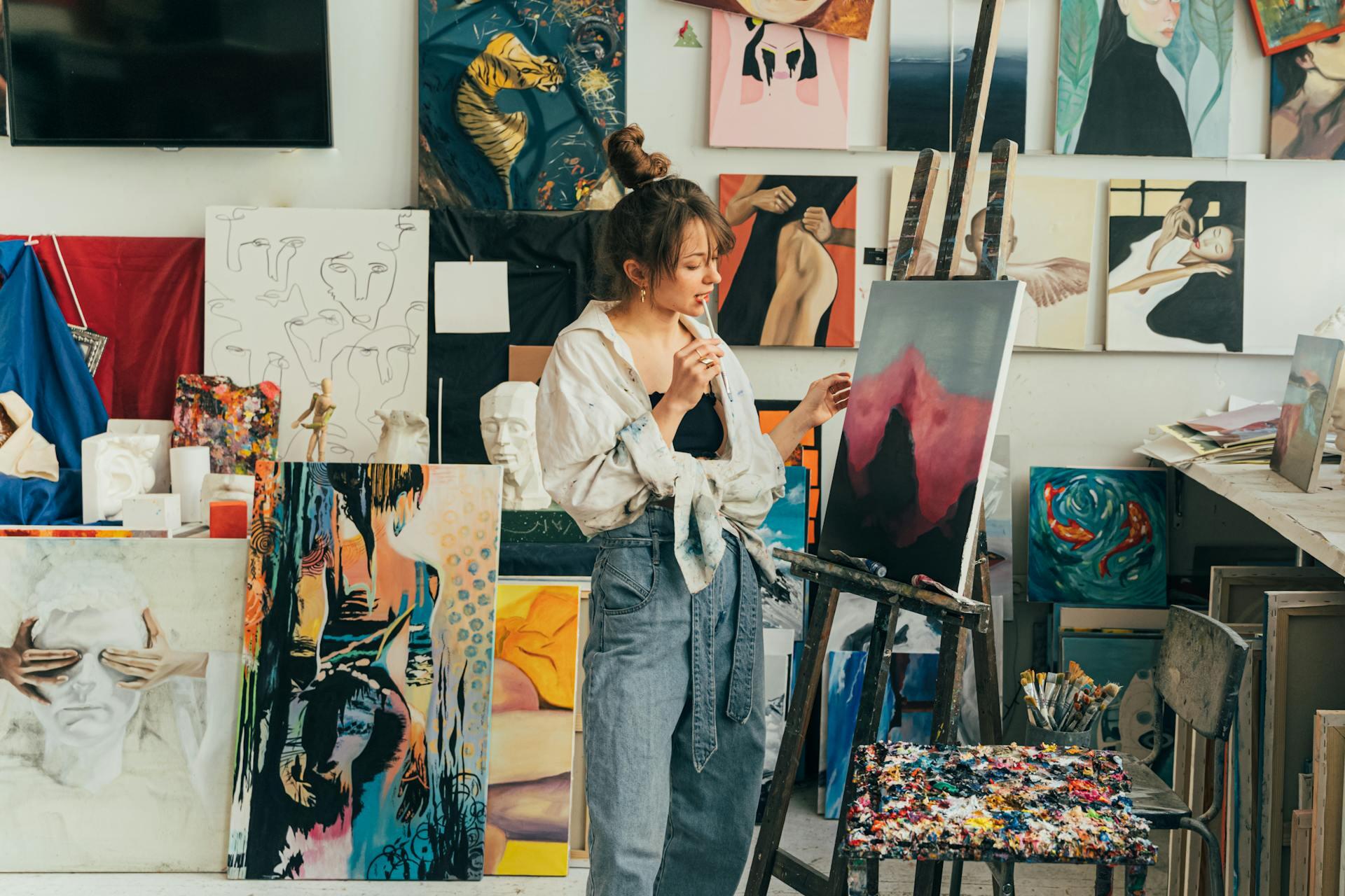 female painter in a studio with paintings all around