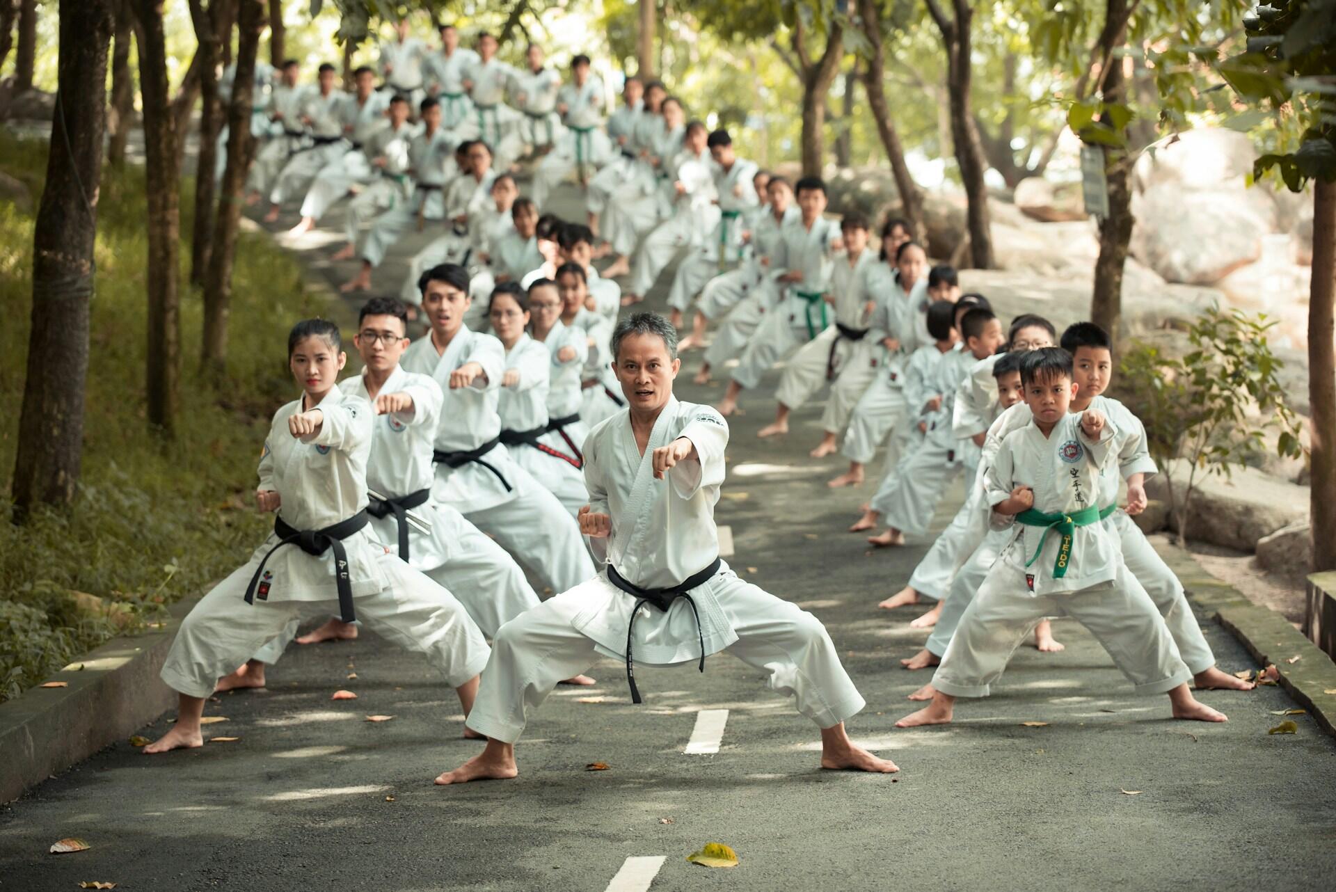 large group of karate students simultaneously practicing a punch, led by their teacher