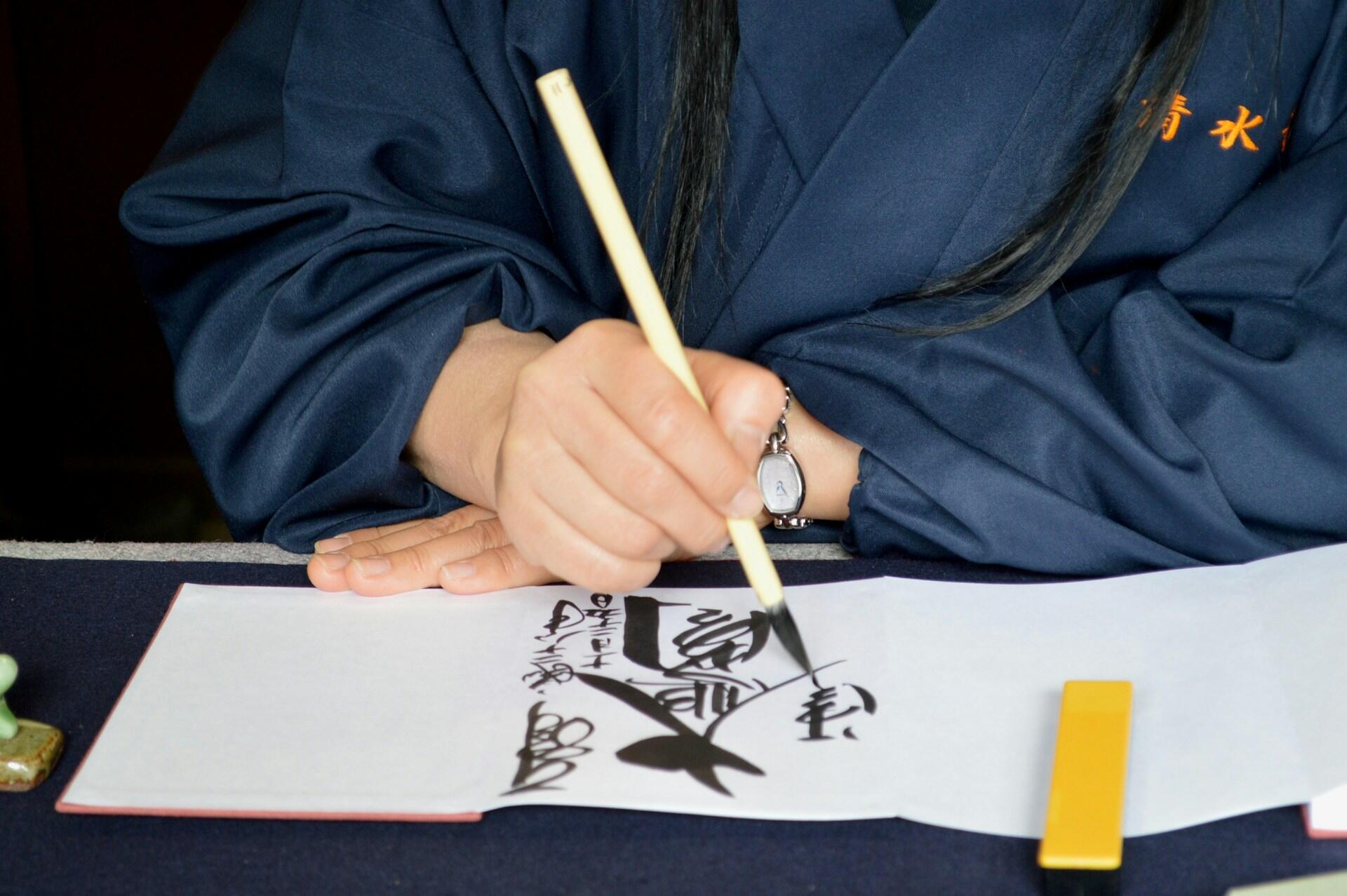 a person writing calligraphy kanji with an ink brush
