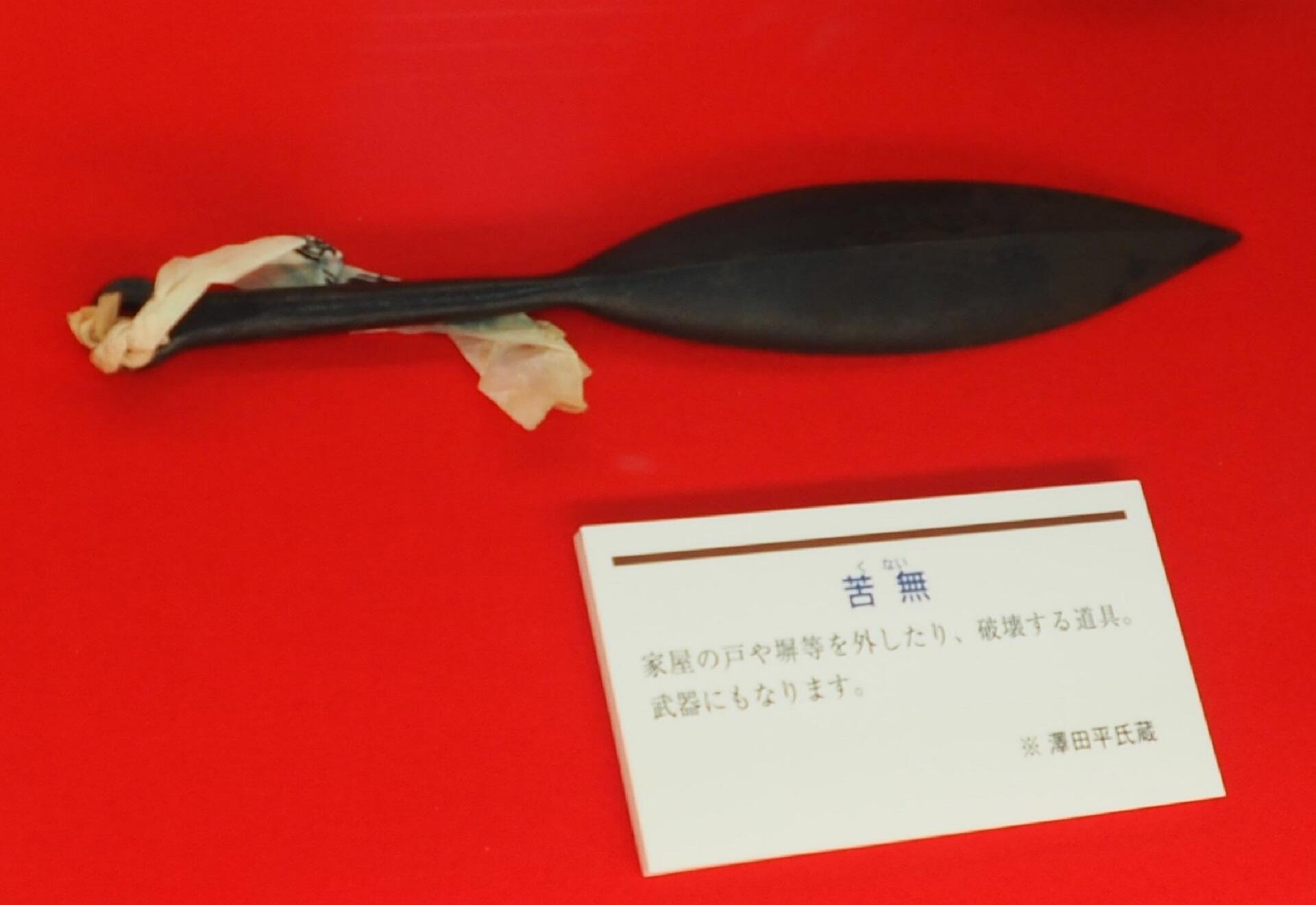 A black spade-like devide with a white string attached on a red background. 