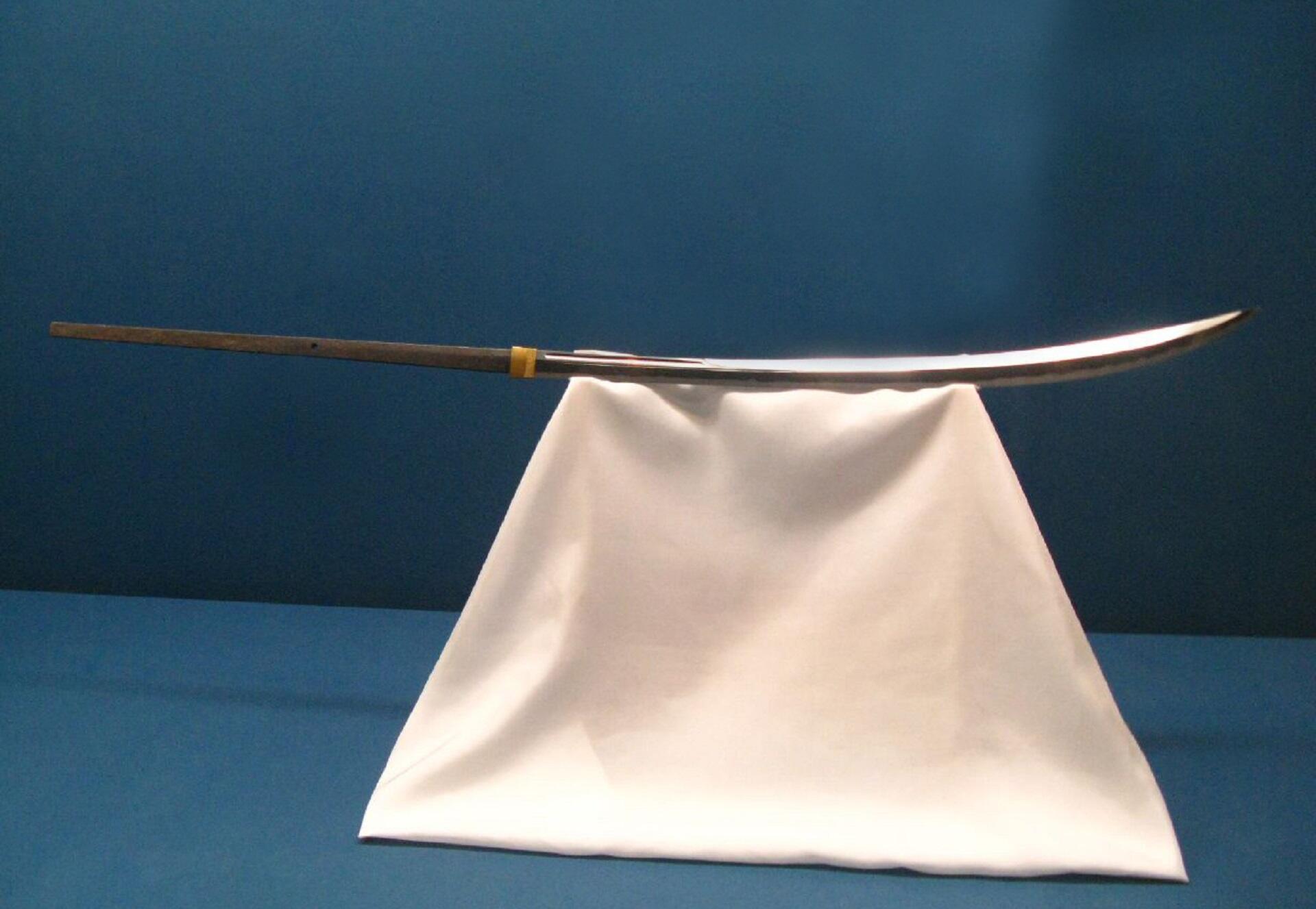 A naginata on a white draped display stand. 