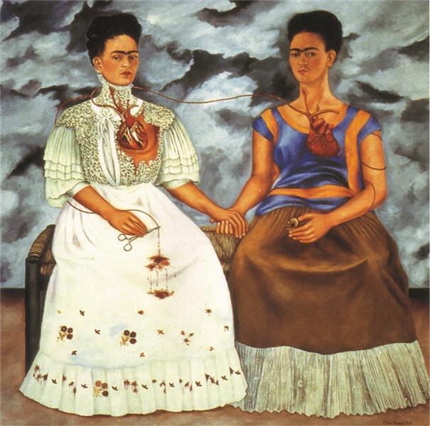 Two women sitting side by side, holding hands, one dressed primly and the other more casually.