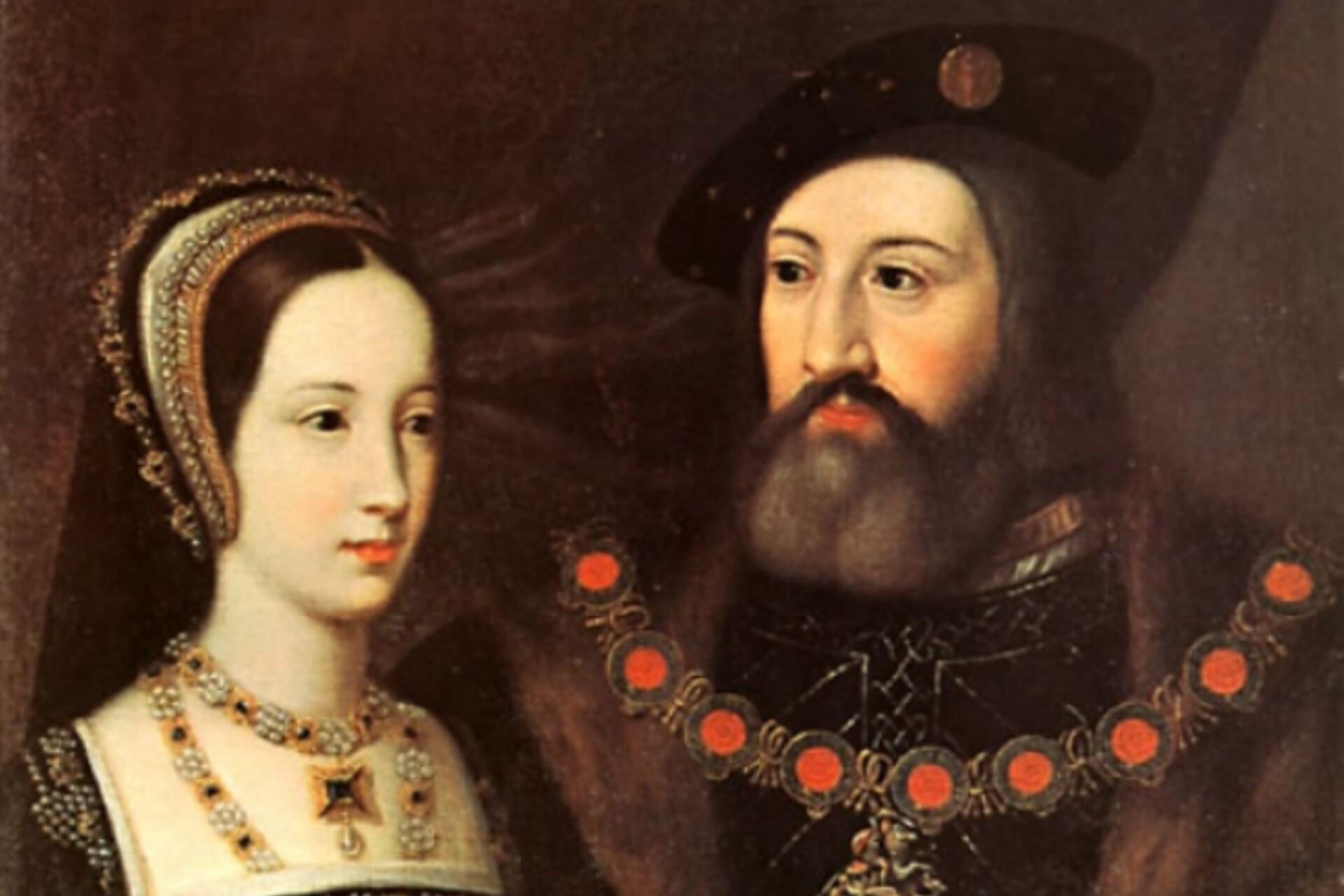 Portrait of a noble couple wearing Tudor clothing, with the woman in a jewelled headdress and necklace beside a bearded man wearing a hat and decorative chain.