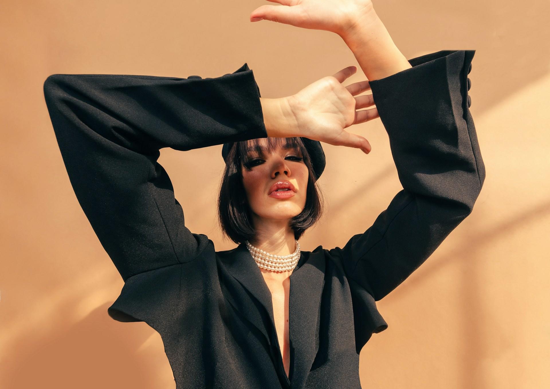 A woman wearing a black suit and a stylish necklace.