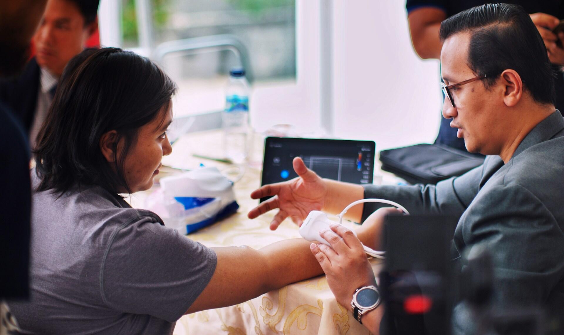 A patient with her arm extended submits to an ultrasound at the doctor's office.