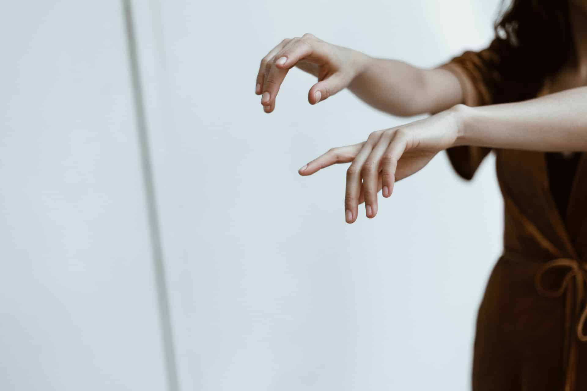 A person in dark coloured clothing with arms outstretched, exercising their hands