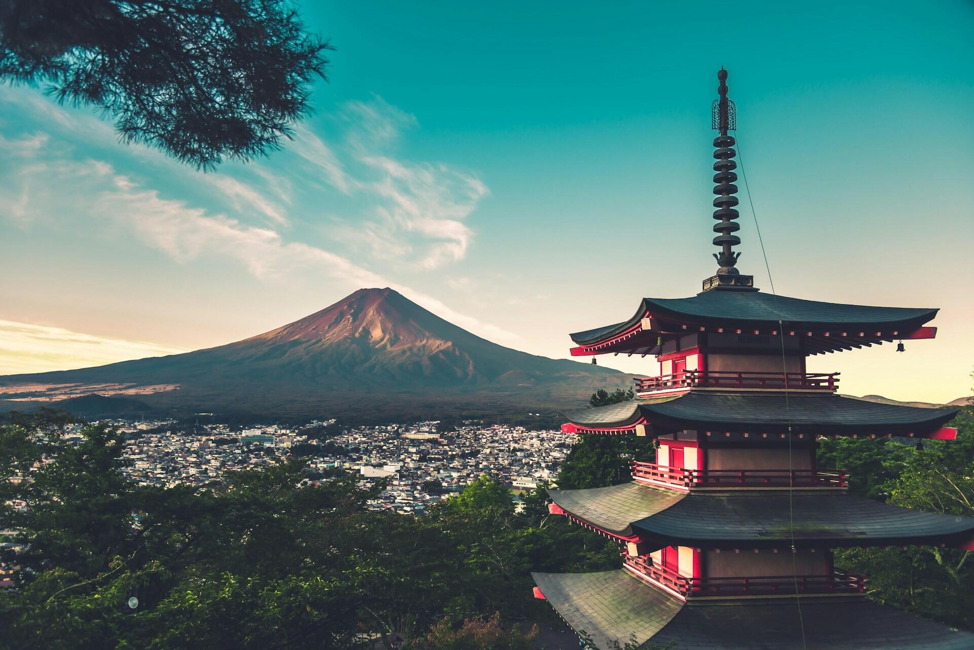Mount Fuji viewed beside a traditional Japanese pagoda overlooking the surrounding town