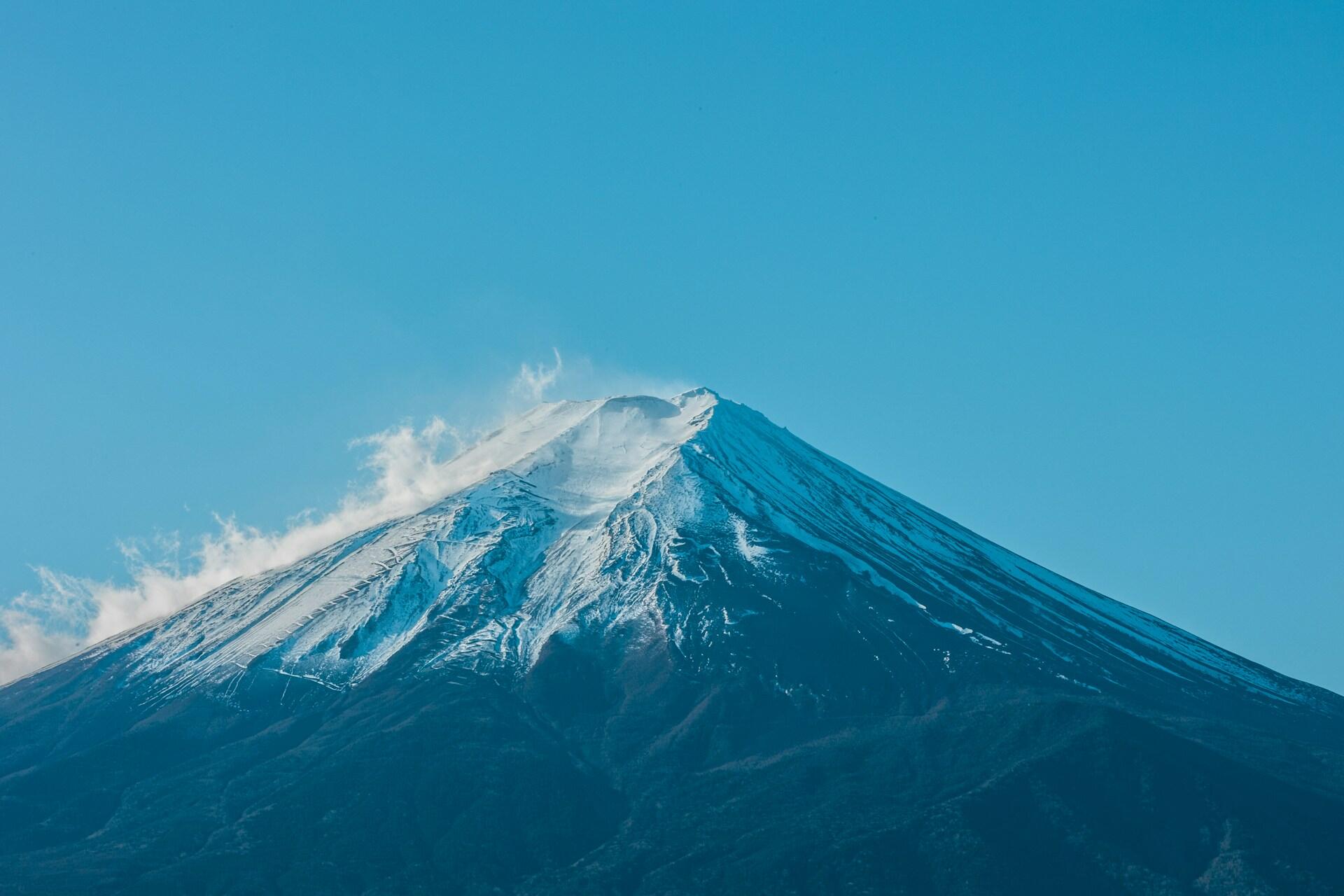 Close-up view of Mount Fuji’s upper slopes and snow-covered summit under clear blue skies