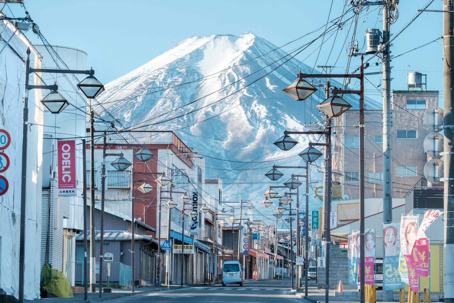 Snow-covered Mount Fuji rising behind a traditional Japanese town street during winter