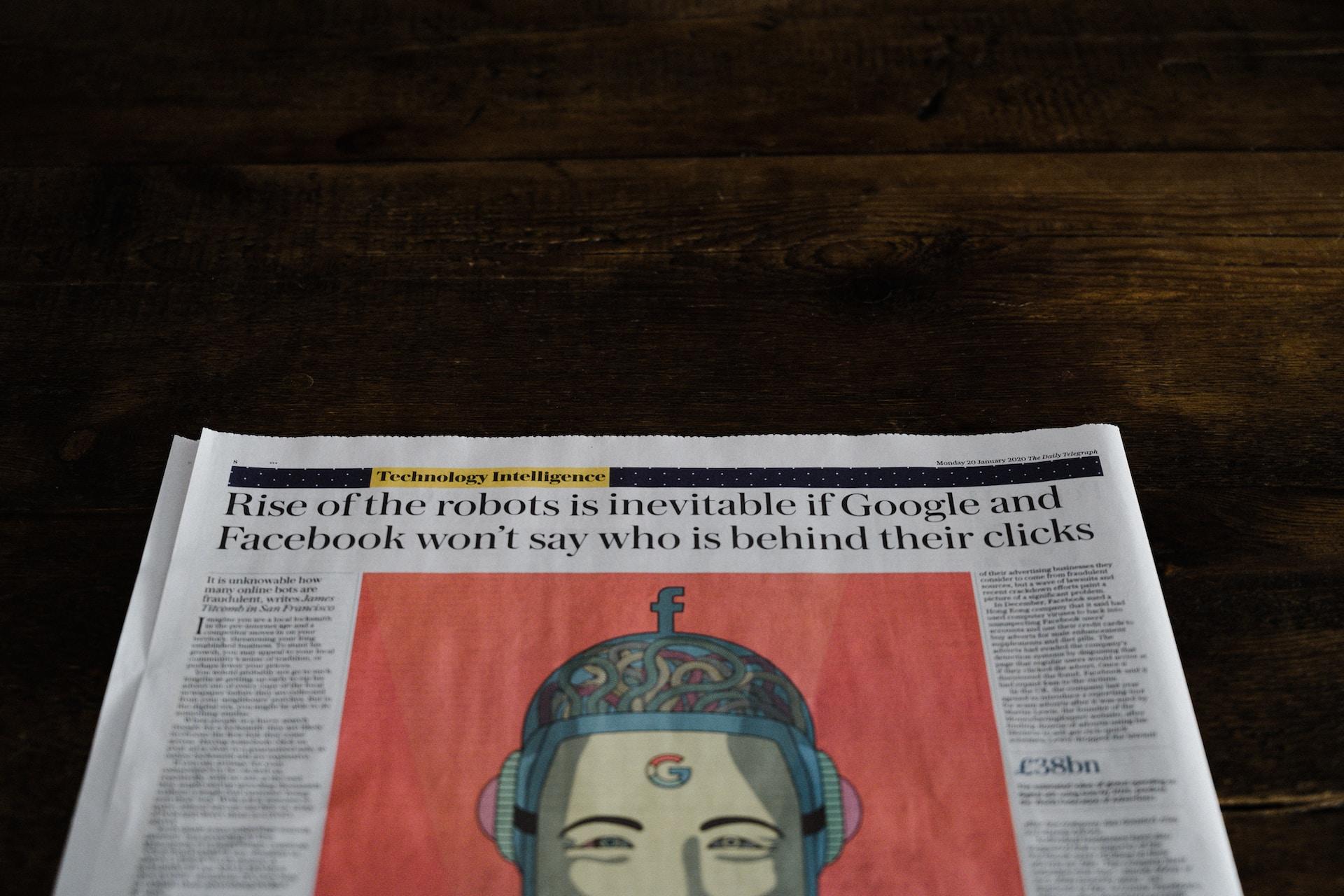 A newspaper with an alarming headline spans the entire page, over two columns of print and an image of a cartoon Zuckerberg with a google logo on its forehead and cogs and gears for brains, set against an orange background.