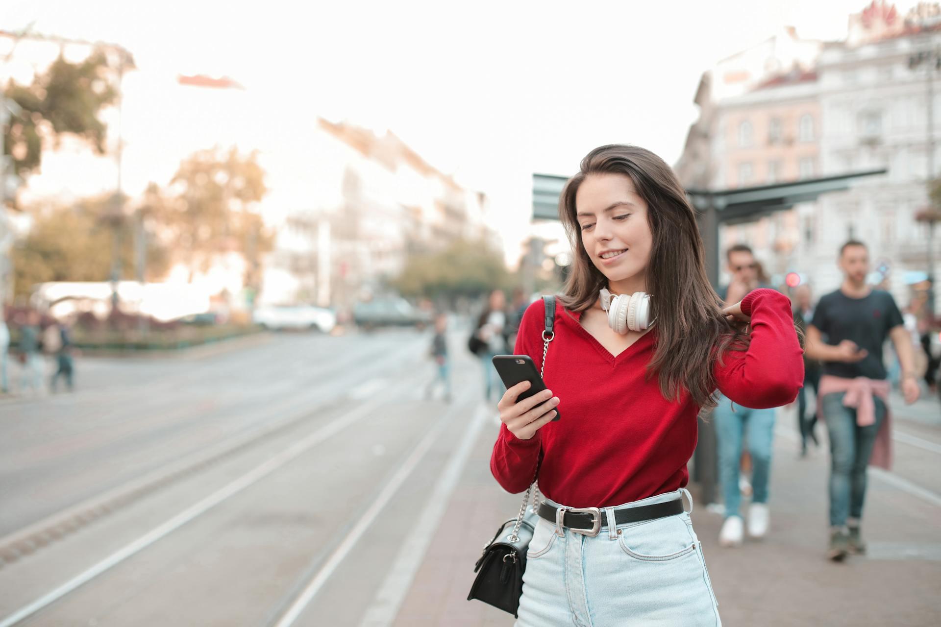 woman out walking on the street and looking at her phone, perhaps taking a lesson on a language app