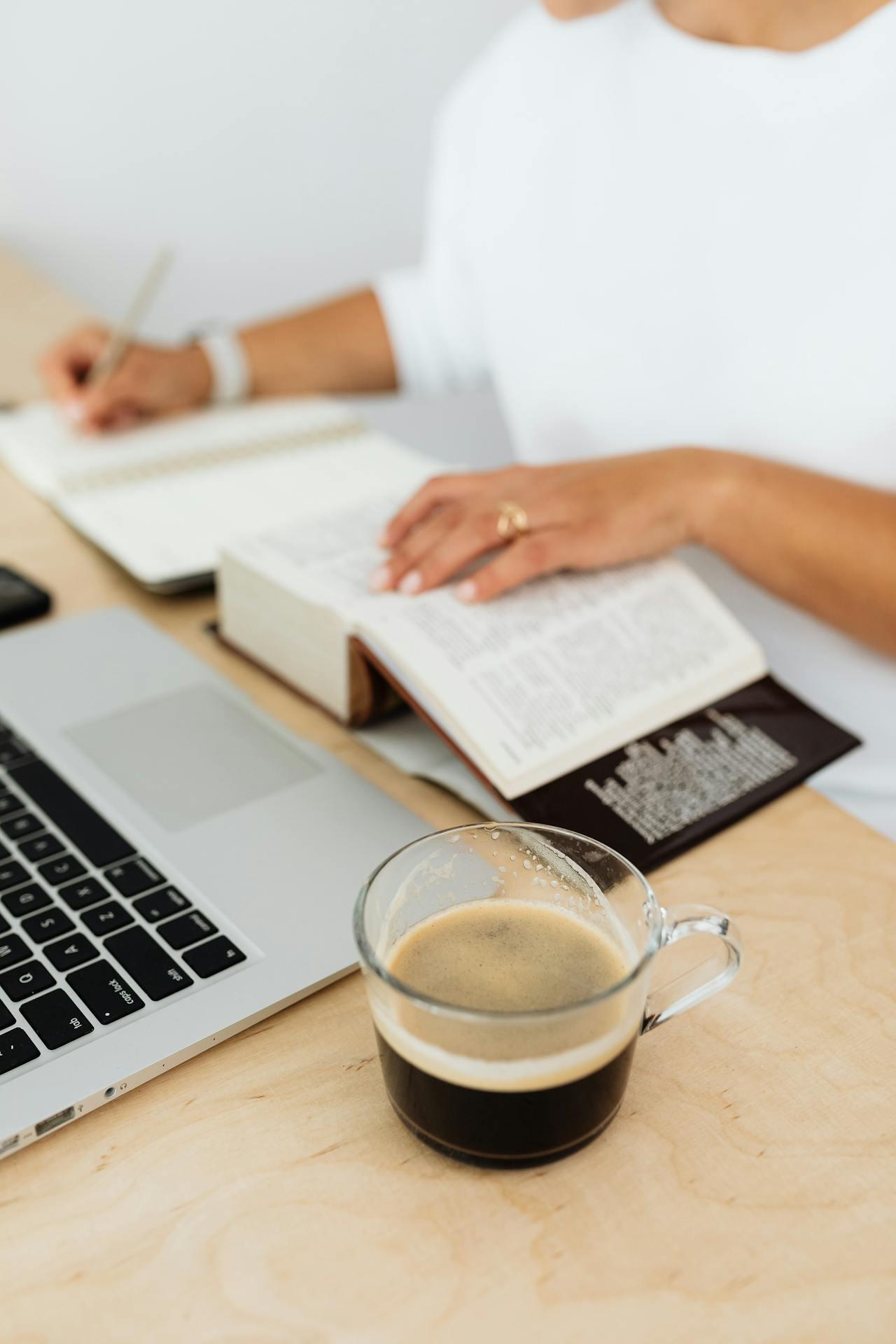 person using a computer and paper dictionary to take notes and learn