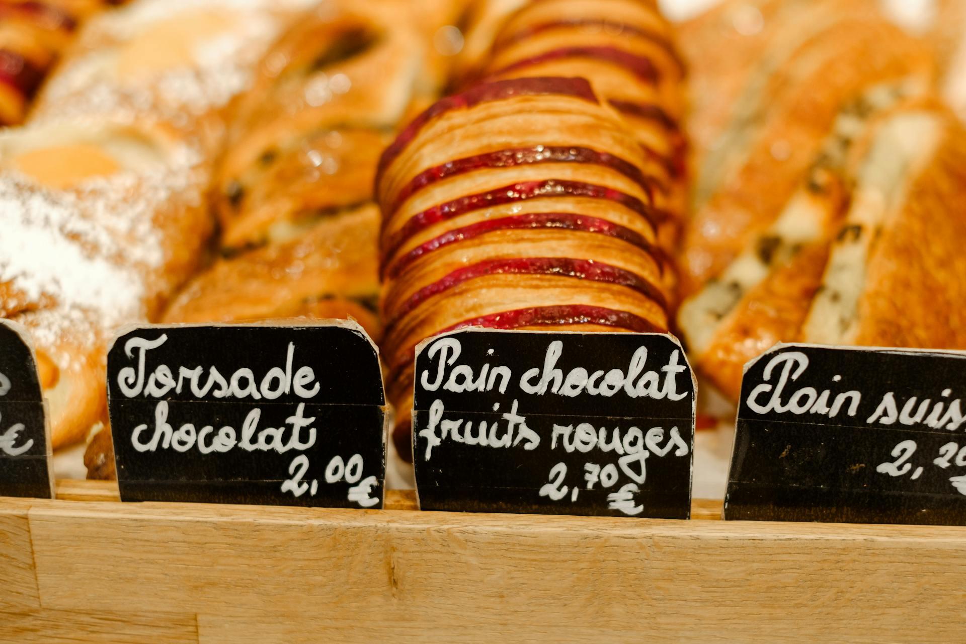 a variety of French pastries on display with signs displaying their names in French