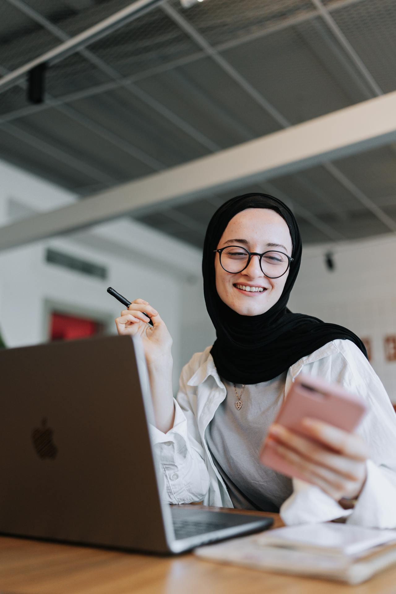 woman using a smartphone and laptop while smiling