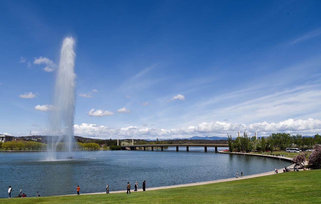 A lake with a water fountain on a sunny day.