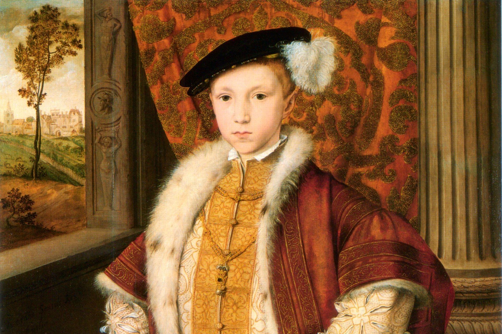 Young boy wearing a red and gold embroidered Tudor outfit with a fur collar and black hat decorated with a white feather, seated in front of a patterned red backdrop.