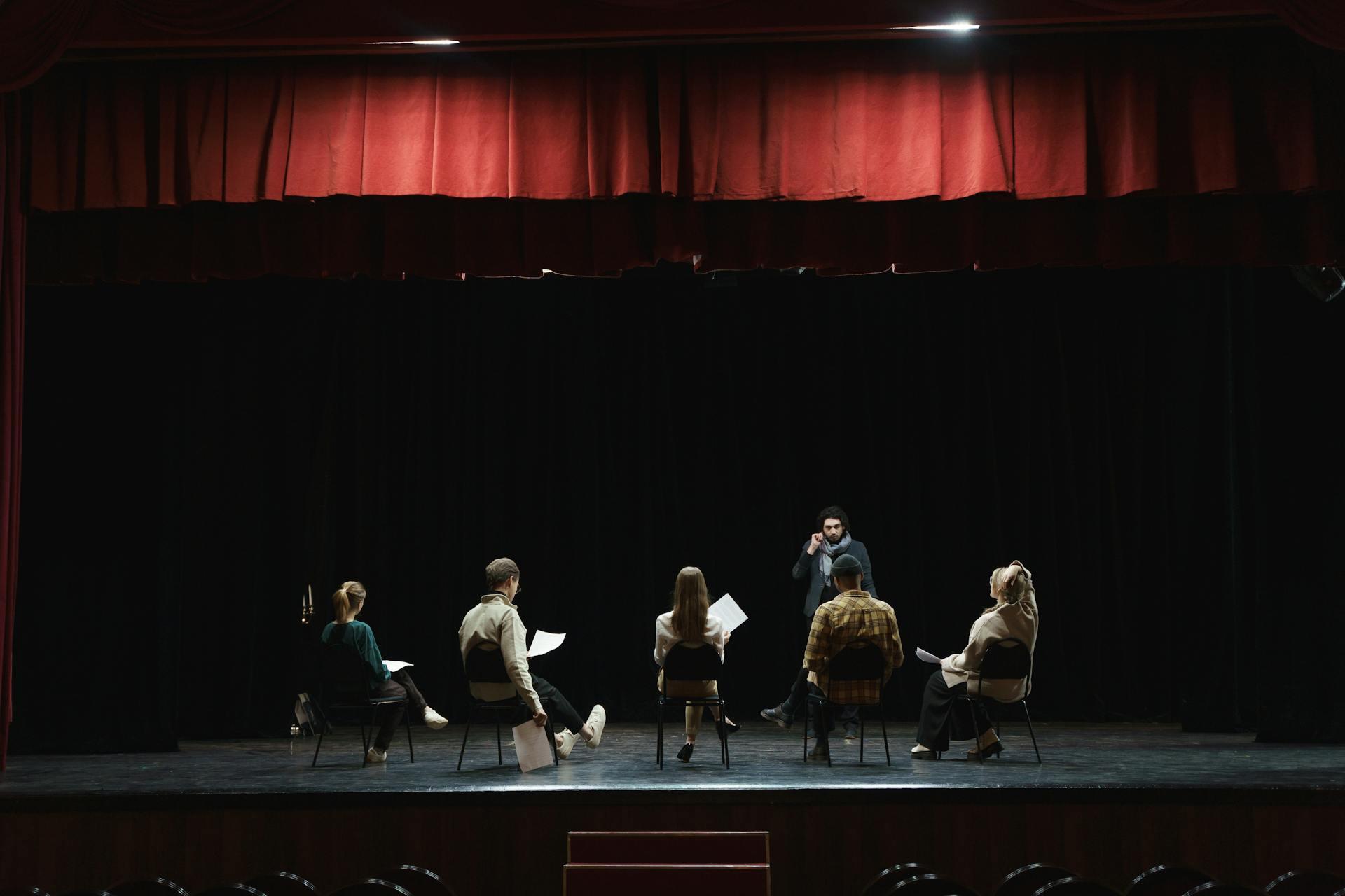 theatre students sitting together on stage rehearsing their lines
