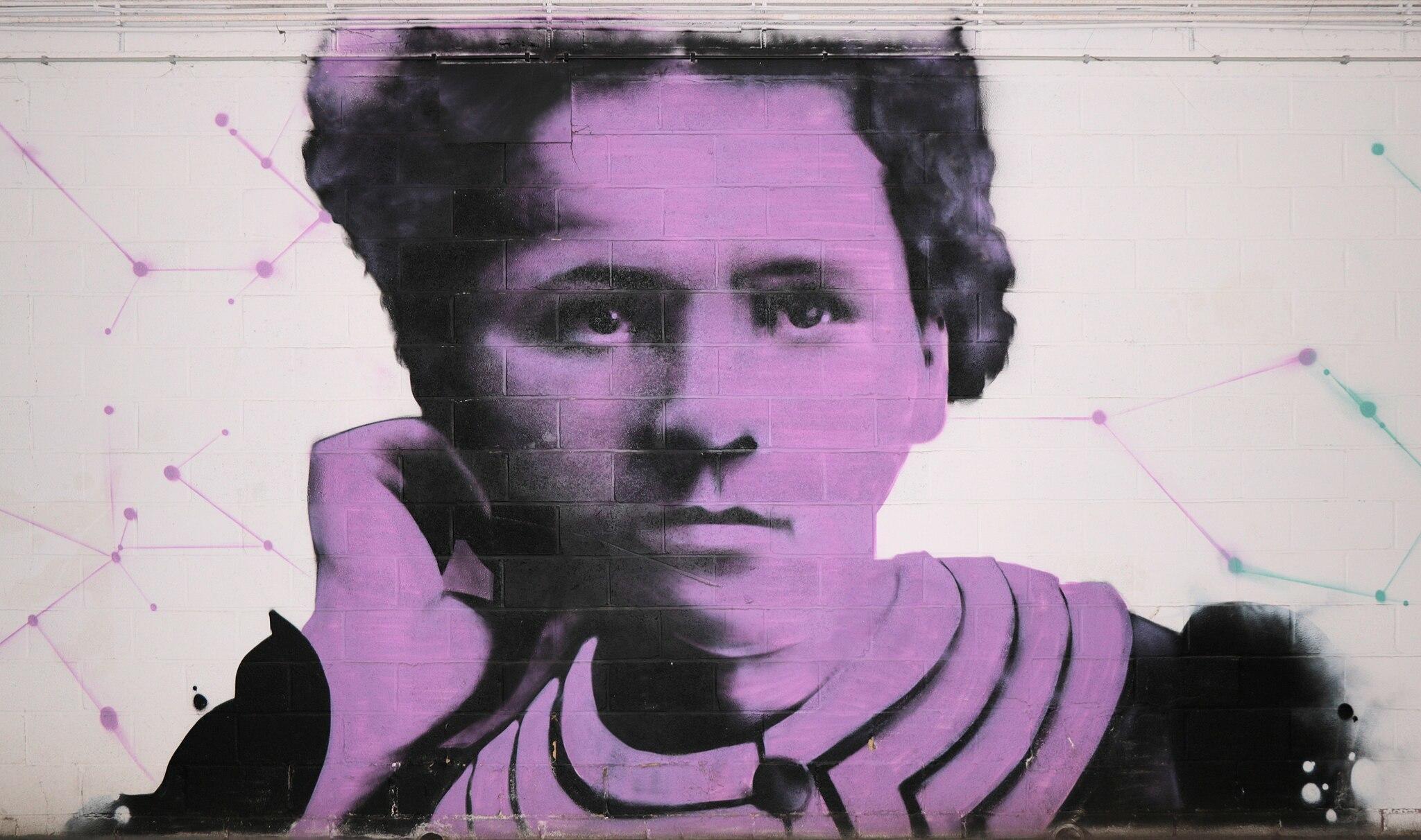 A purple mural of Marie Curie