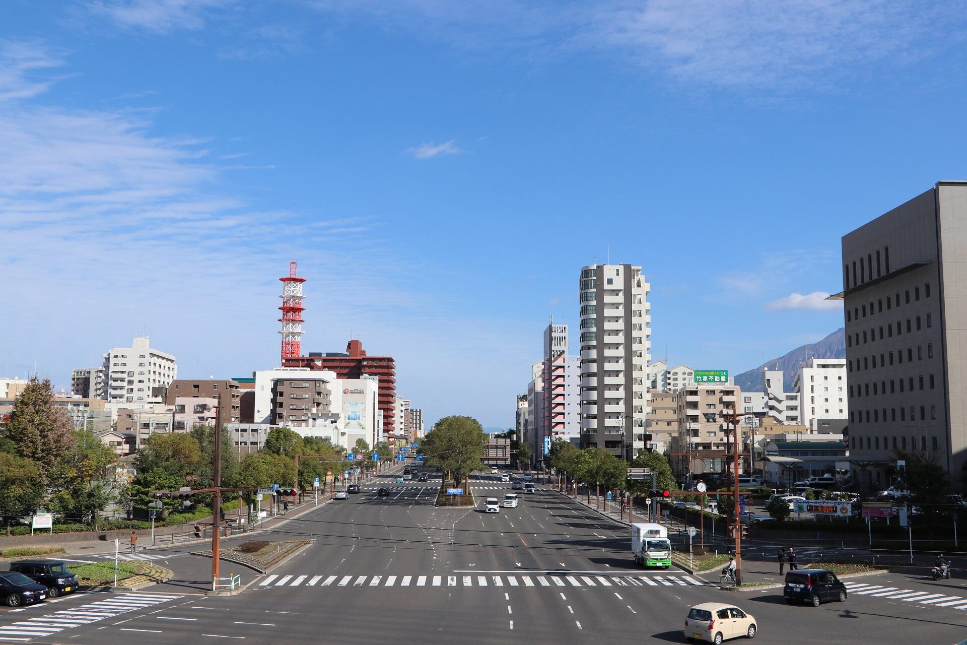 A broad avenue with little traffic on a sunny day. 