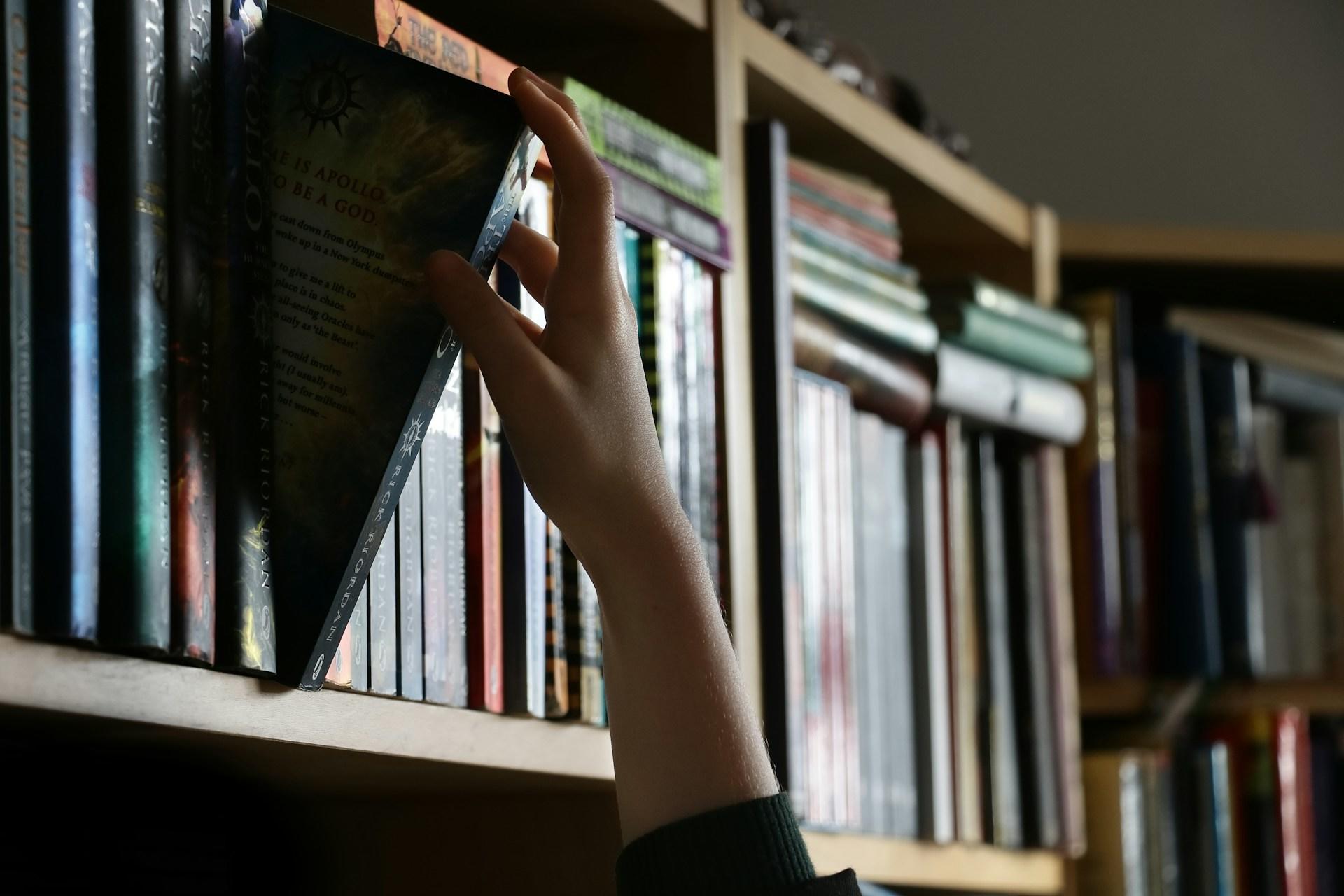A student removing a book from a shelf.