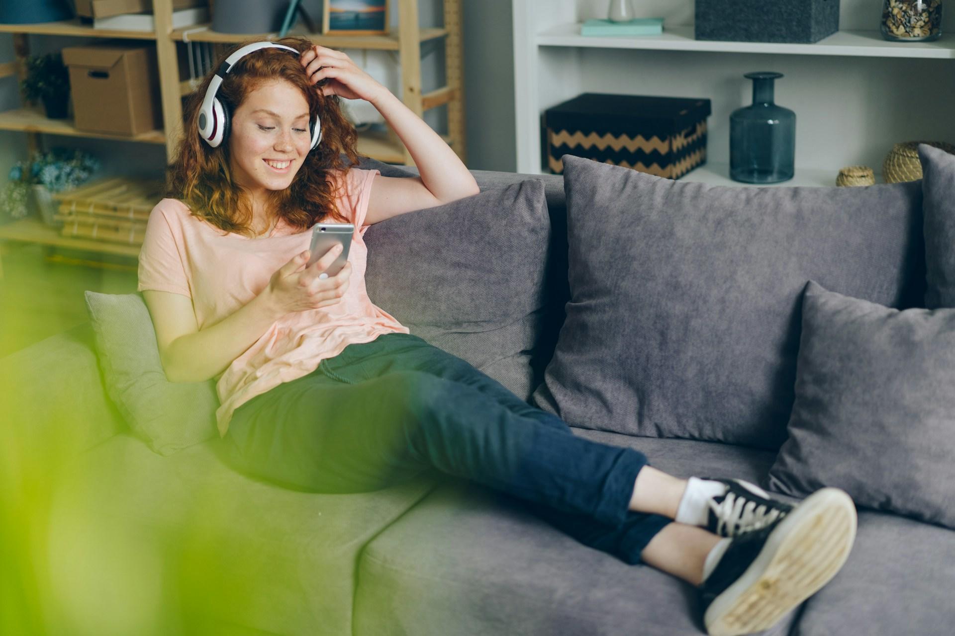 A student sitting on a sofa listening.