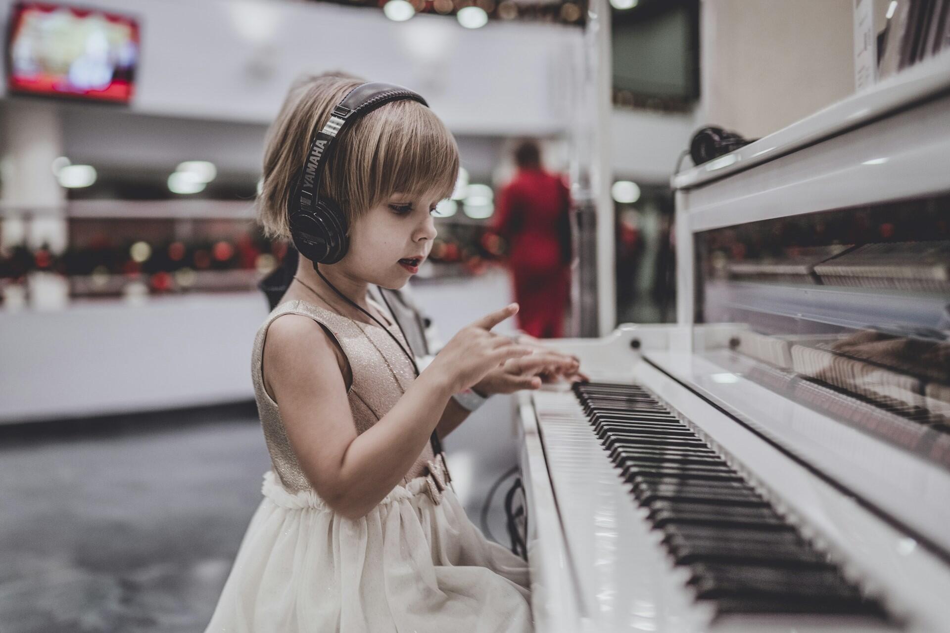 A little girl playing piano with headphones on.