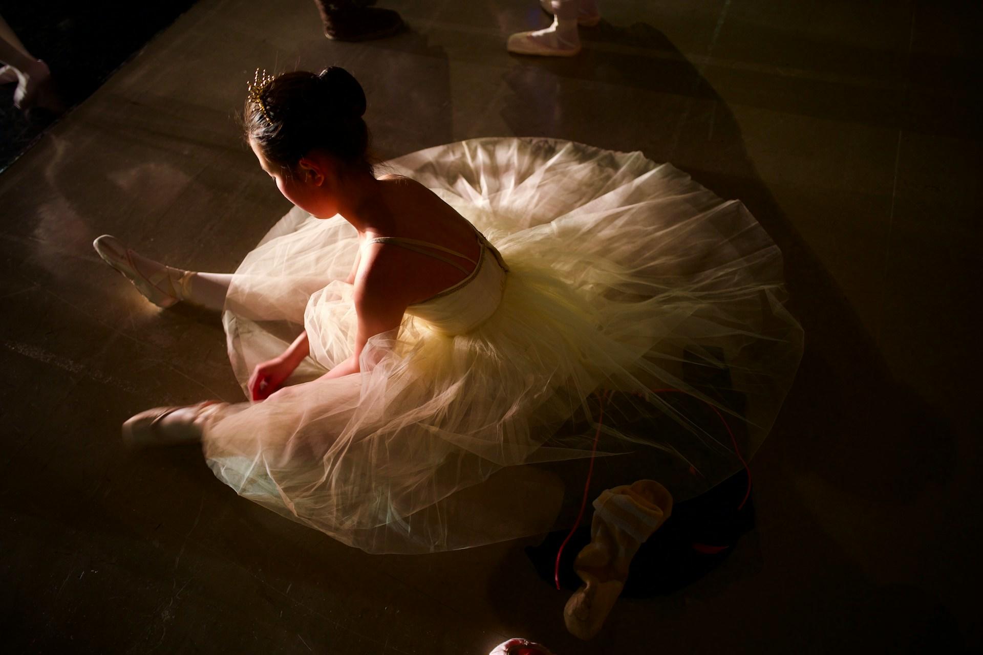 A ballet dancer sitting on a floor.
